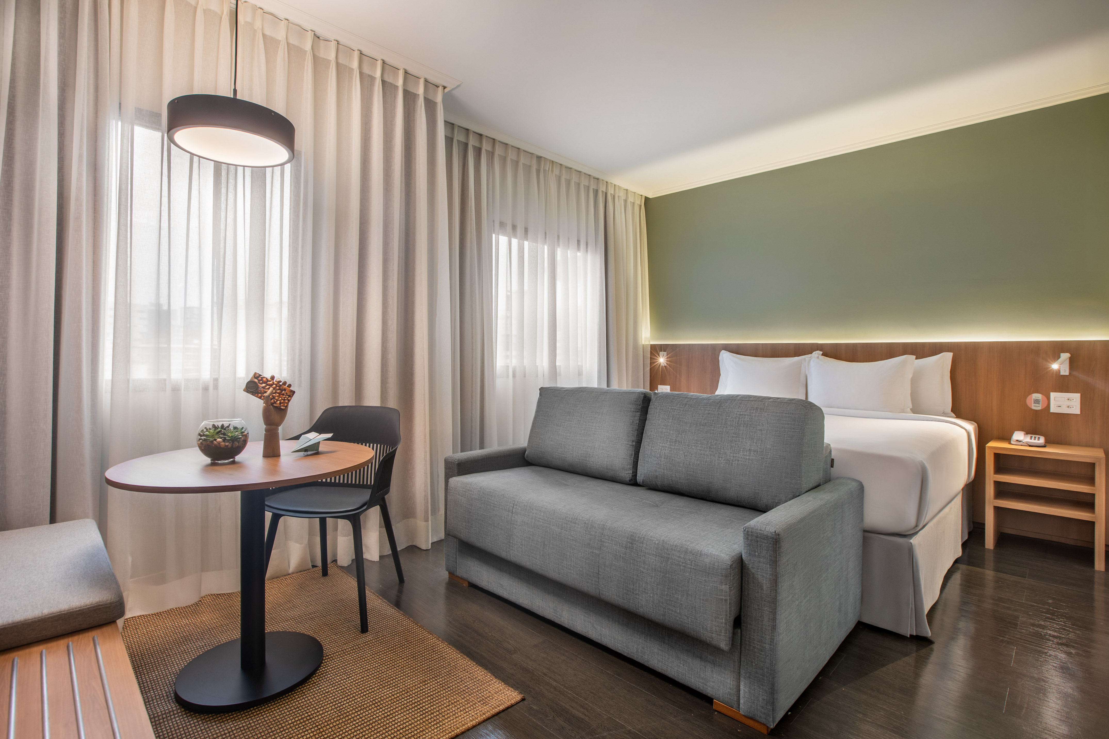 Habitación de hotel moderna con cama, sofá cama y zona de estar.