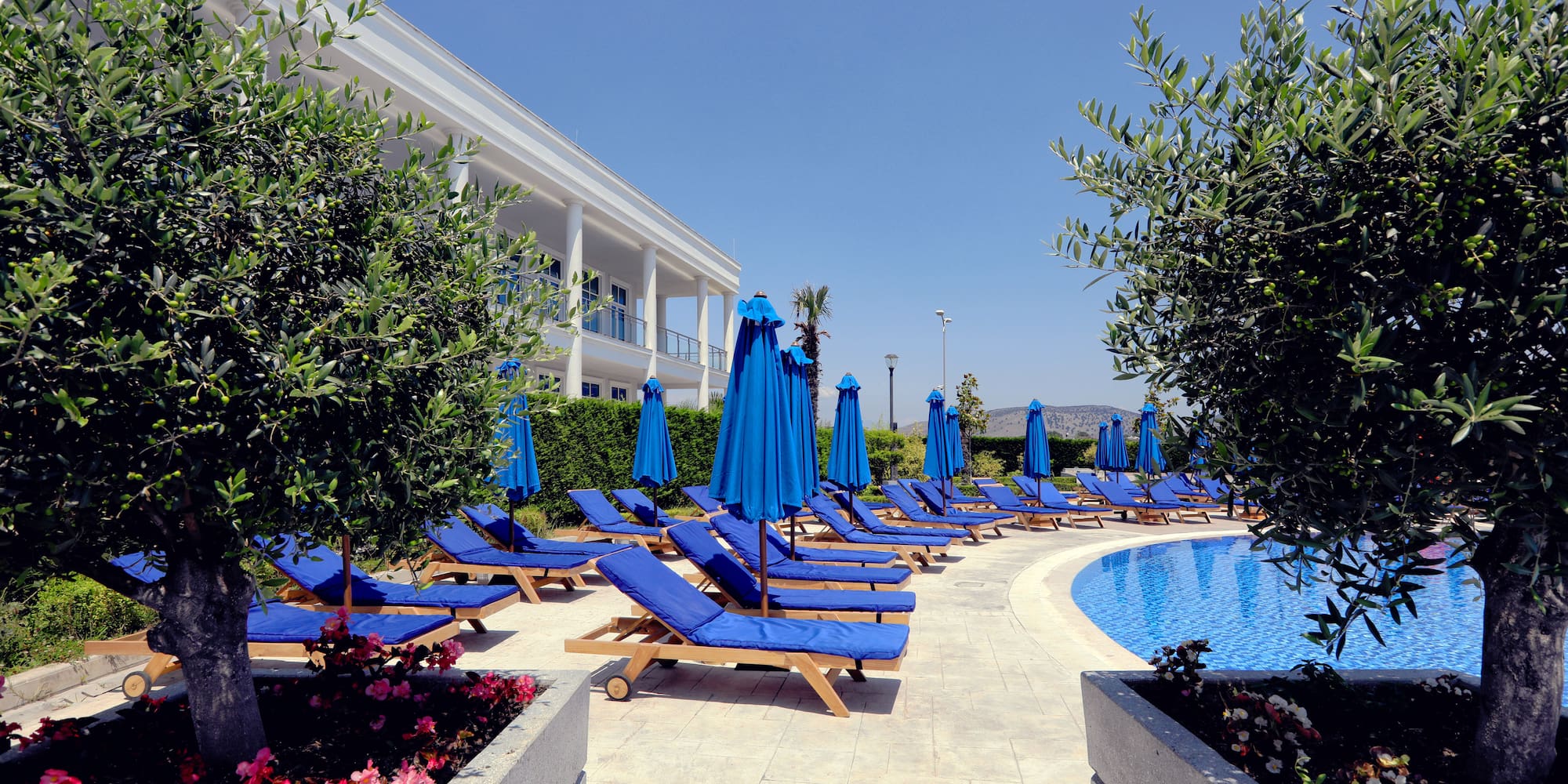 a pool with blue chairs and umbrellas