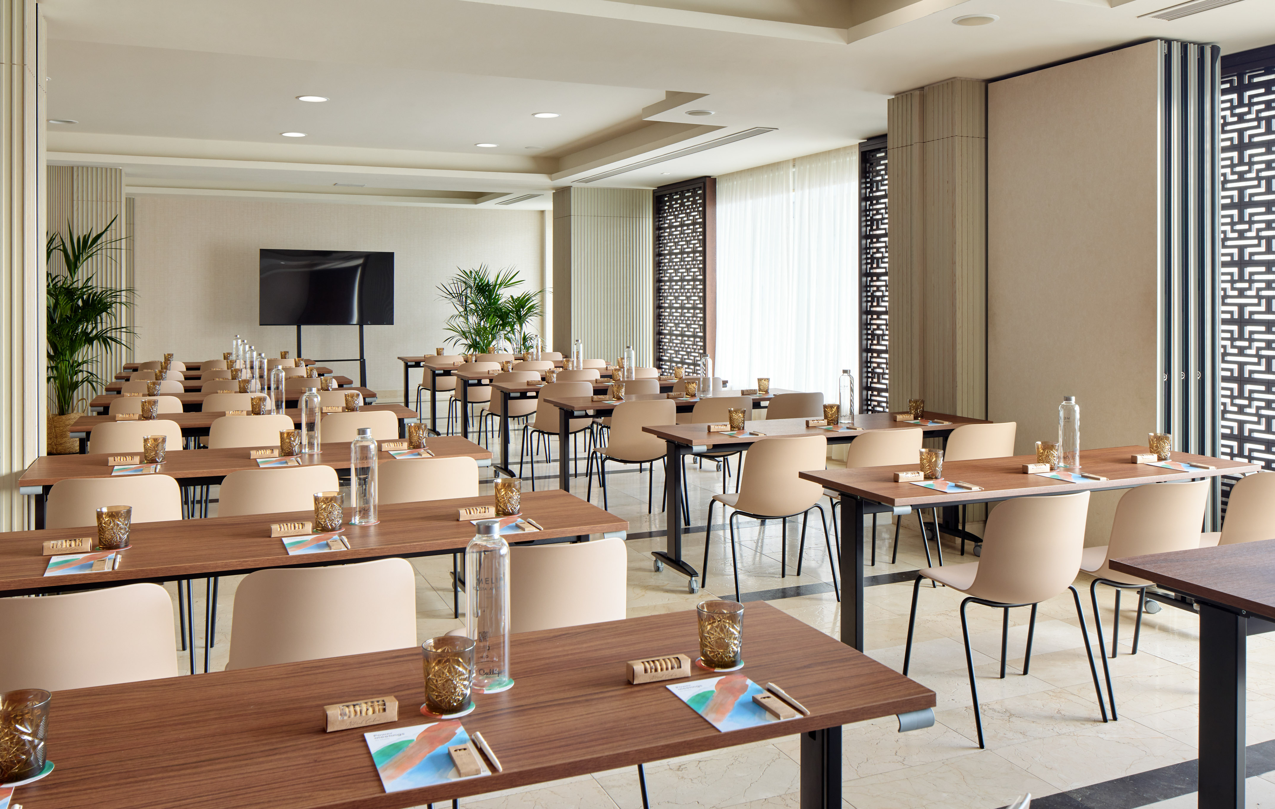 Modern conference room with classroom setup and large presentation screen.