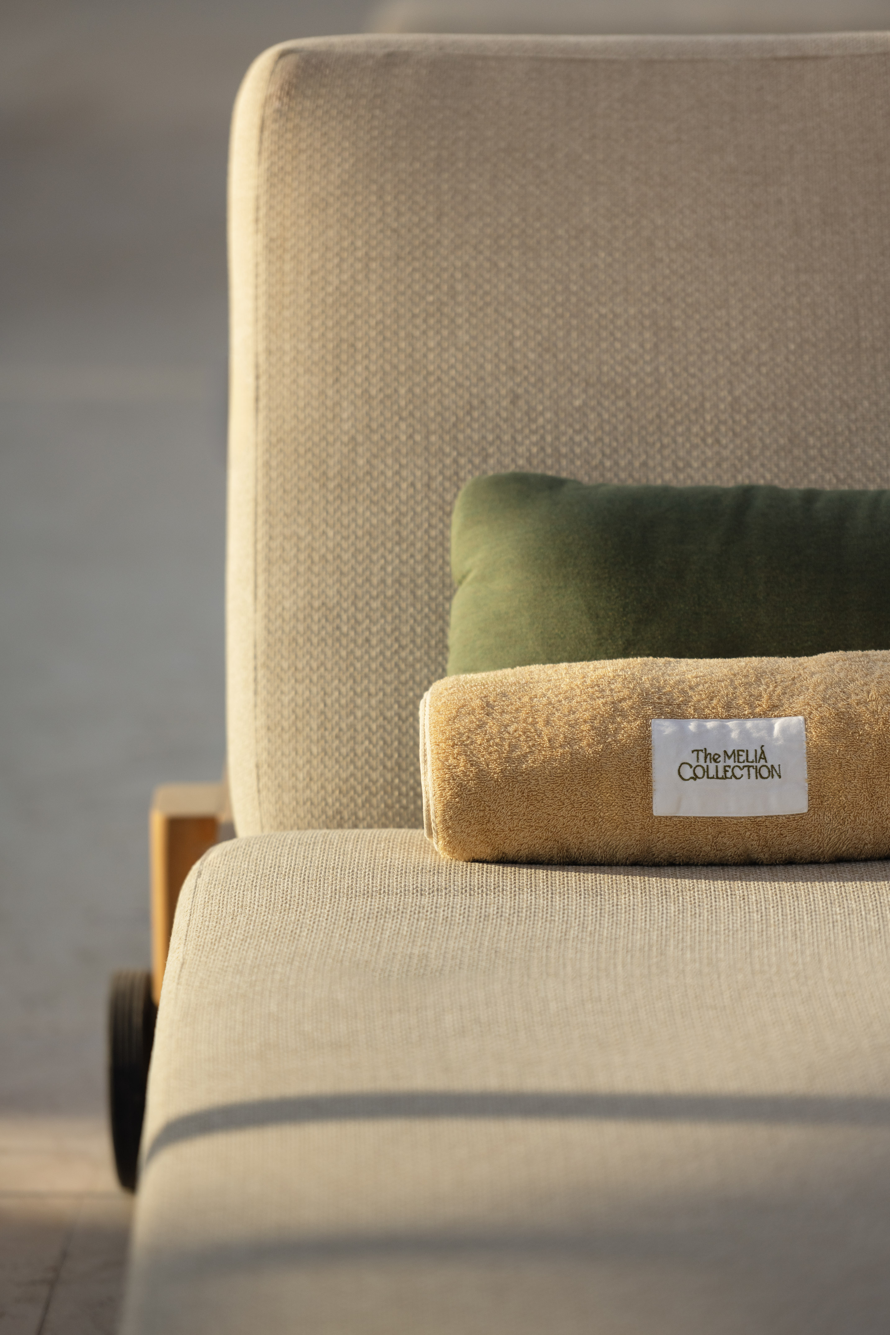 Meliá Collection towel on a luxury sun lounger with green pillow.