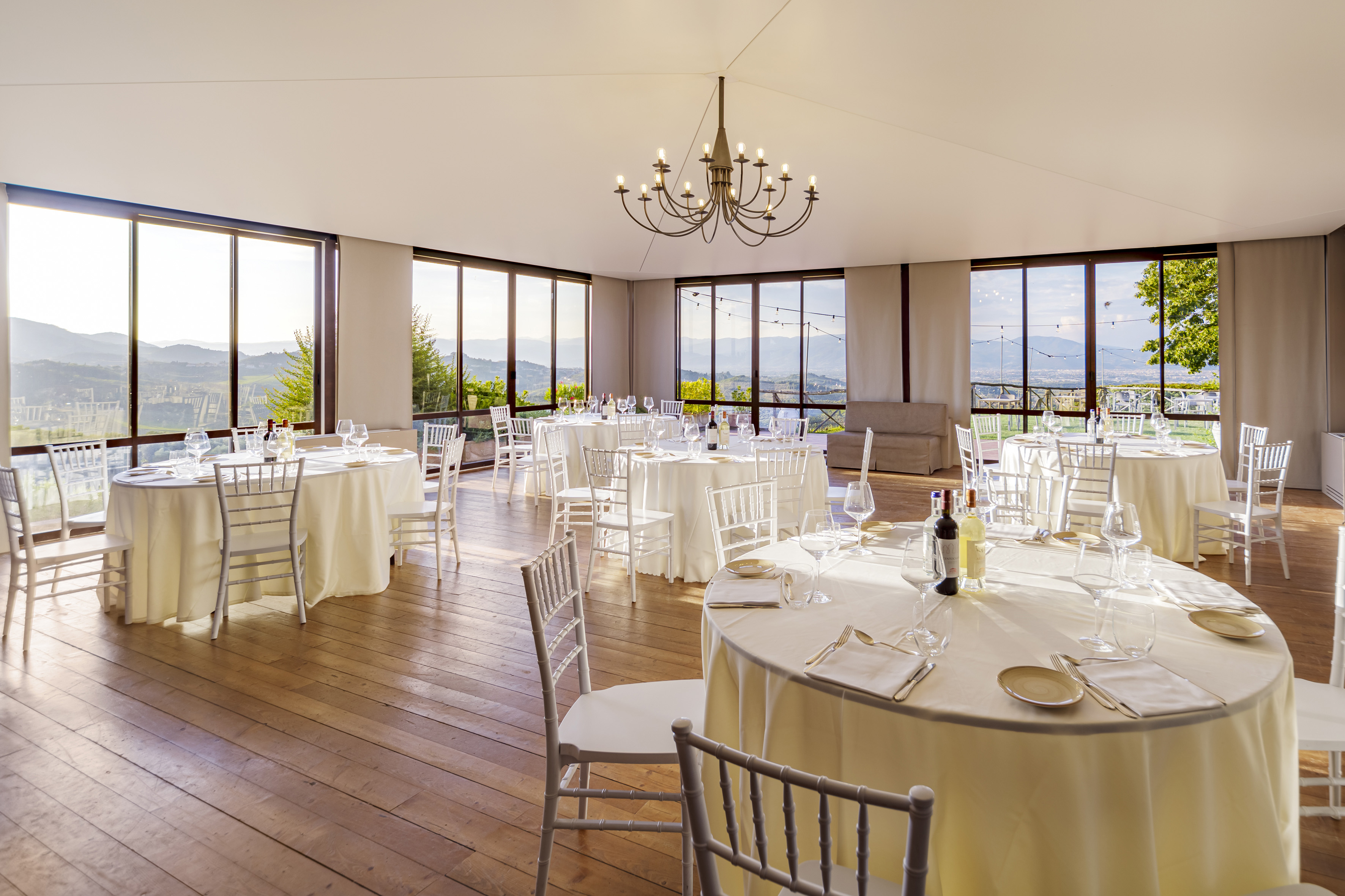 Elegant event hall with set banquet tables, panoramic views, and a chandelier.