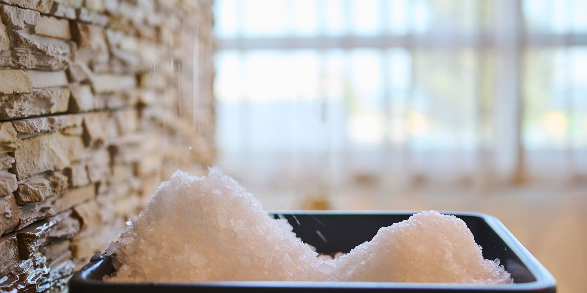 a bowl of salt in front of a stone wall