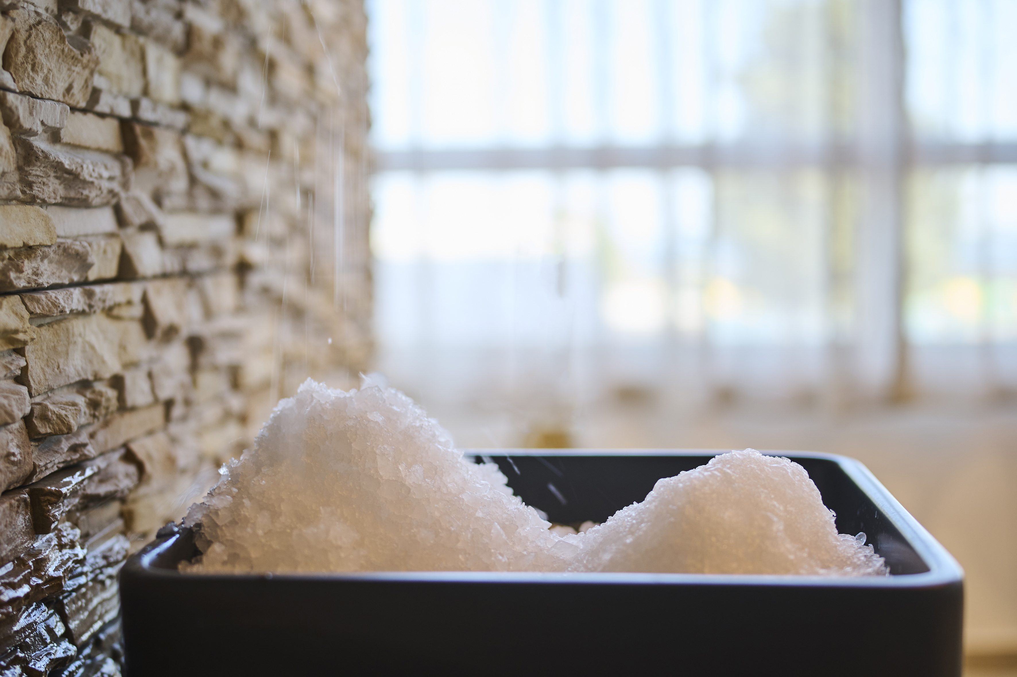 a bowl of salt in front of a stone wall