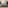Modern dining room with oval table, beige chairs, gold chandelier, artwork, and built-in TV.