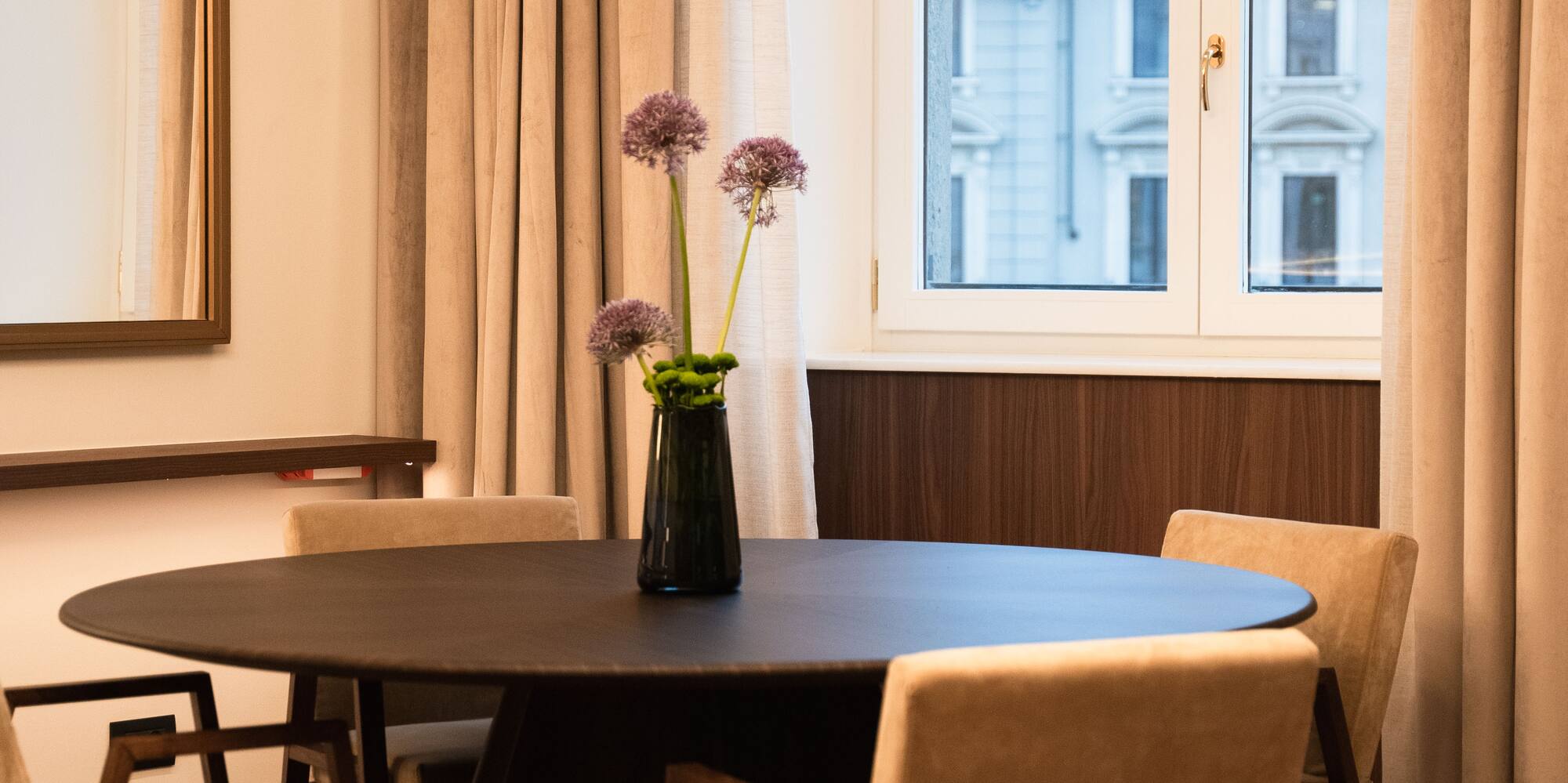 a table with chairs and a vase of flowers