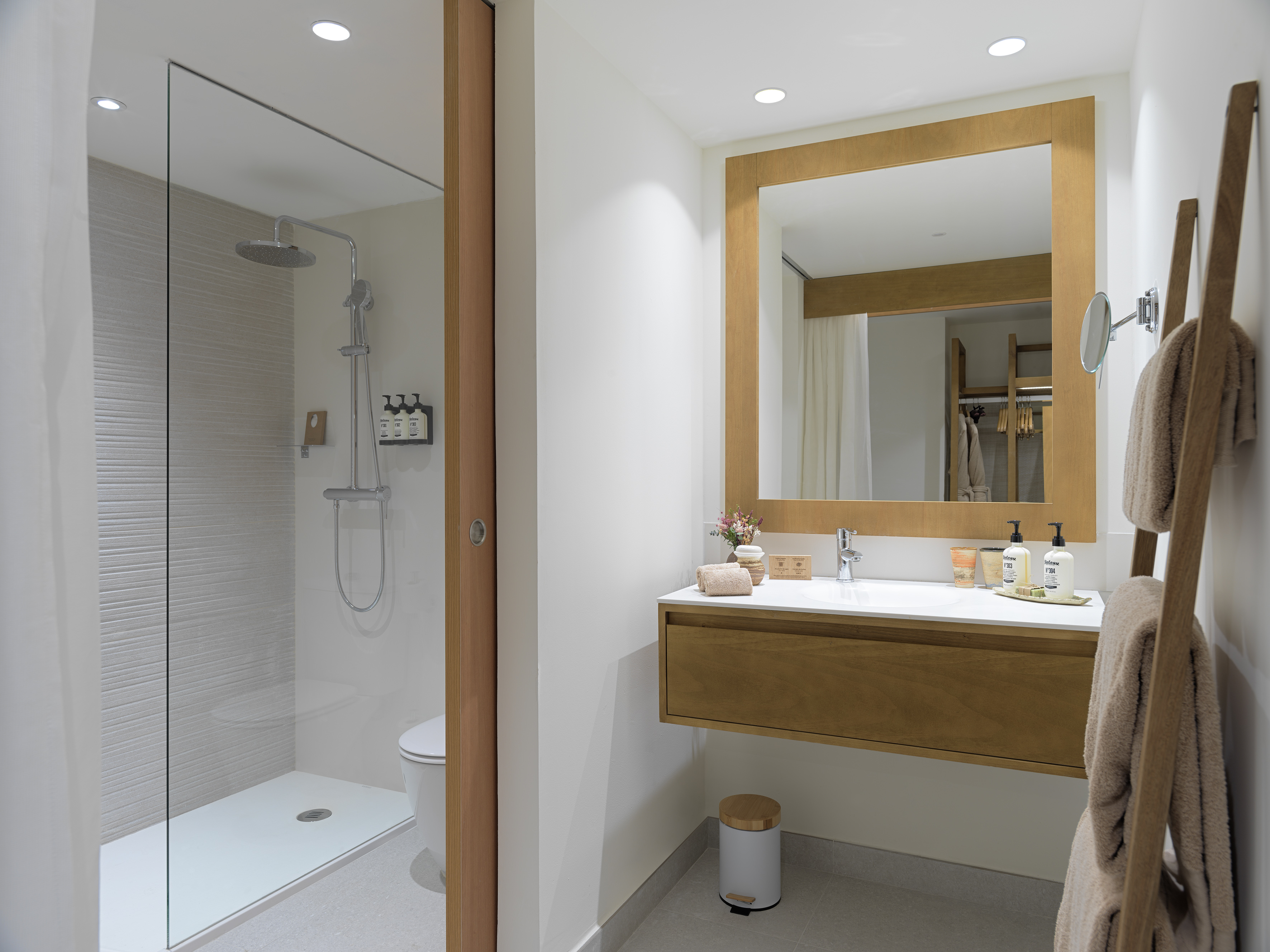 Modern bathroom with walk-in glass shower, floating wood vanity, and sleek design.