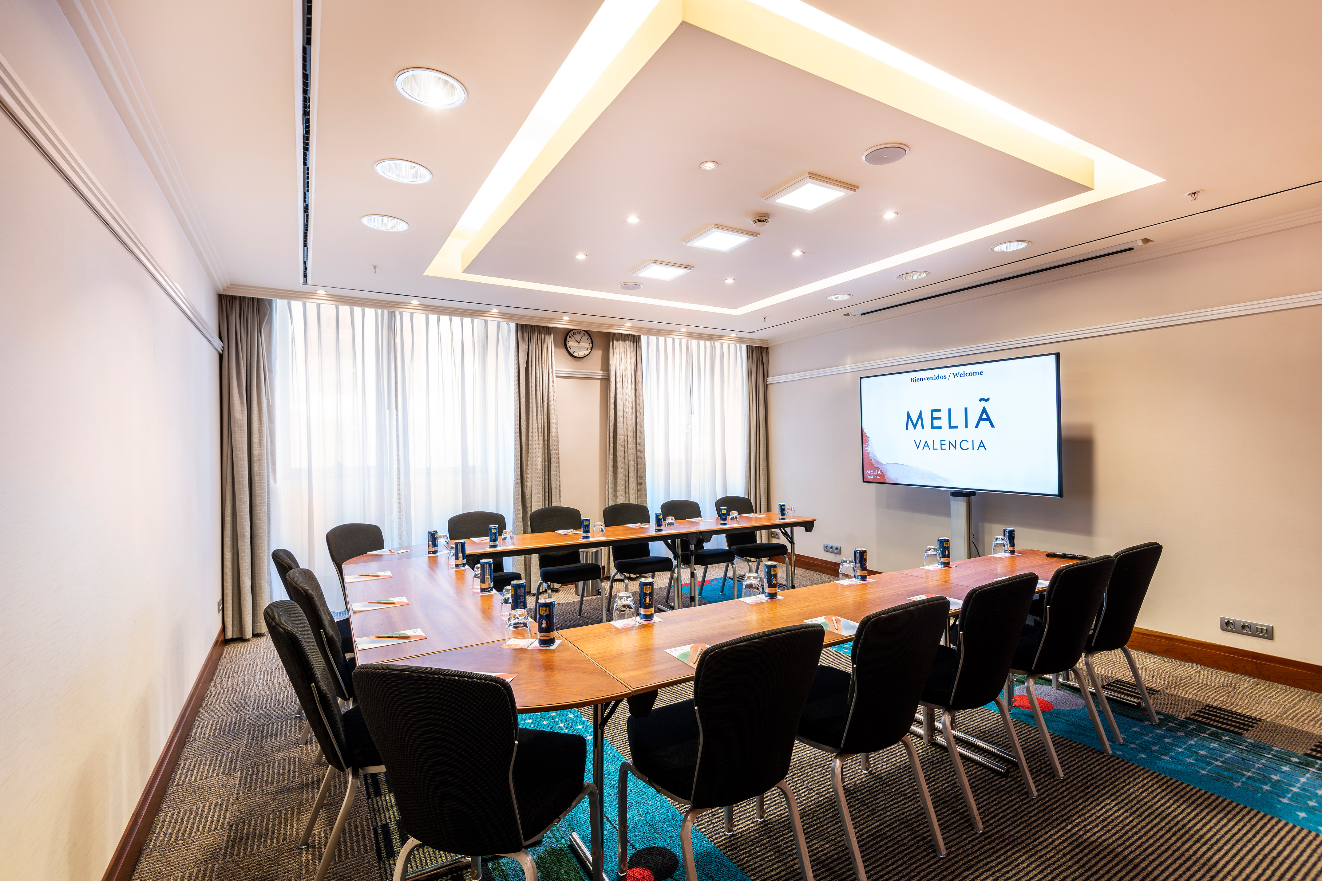 Meliá Valencia meeting room with U-shaped table and large display screen.