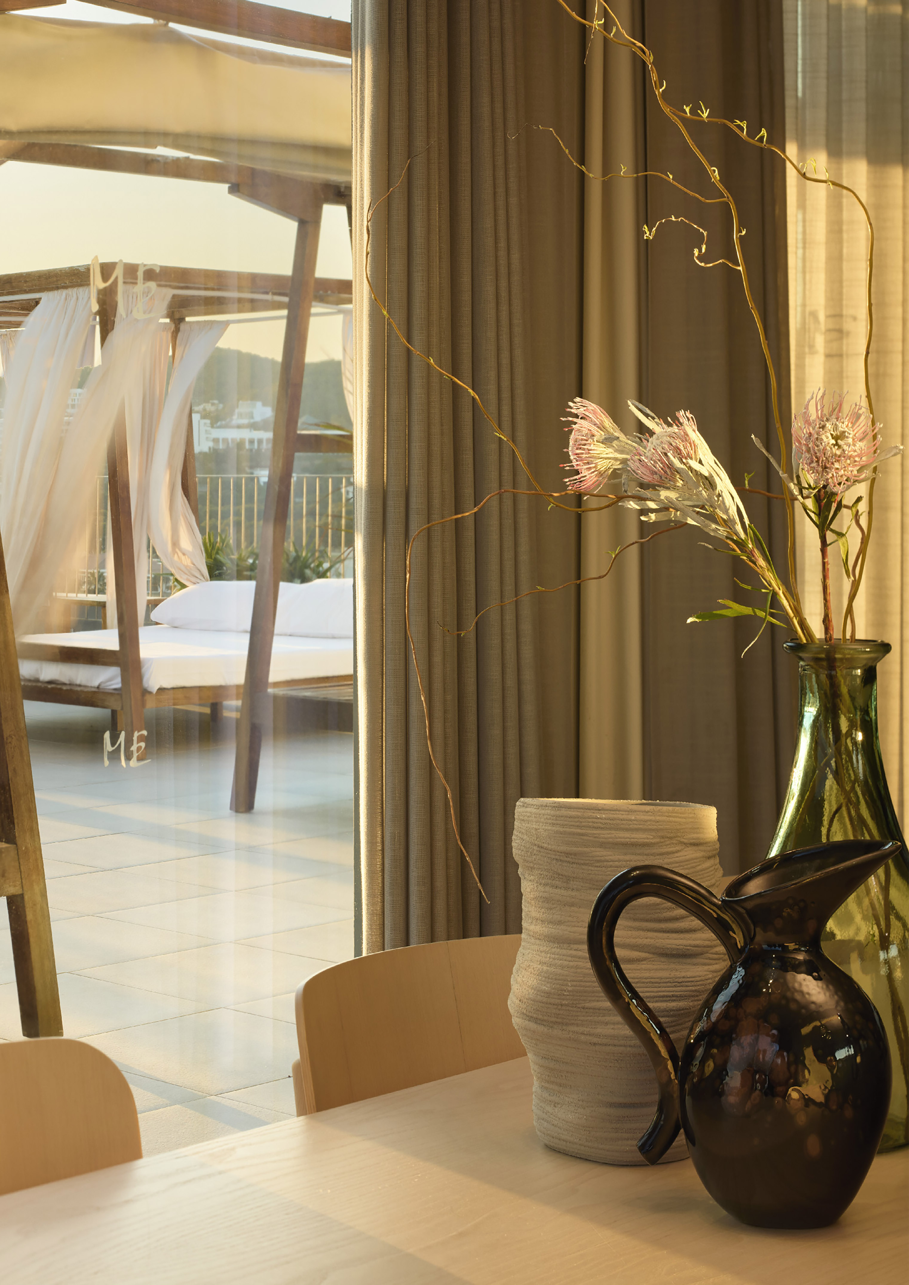 Luxurious room with flowers, dark pitcher, and sunny patio with canopy daybed.
