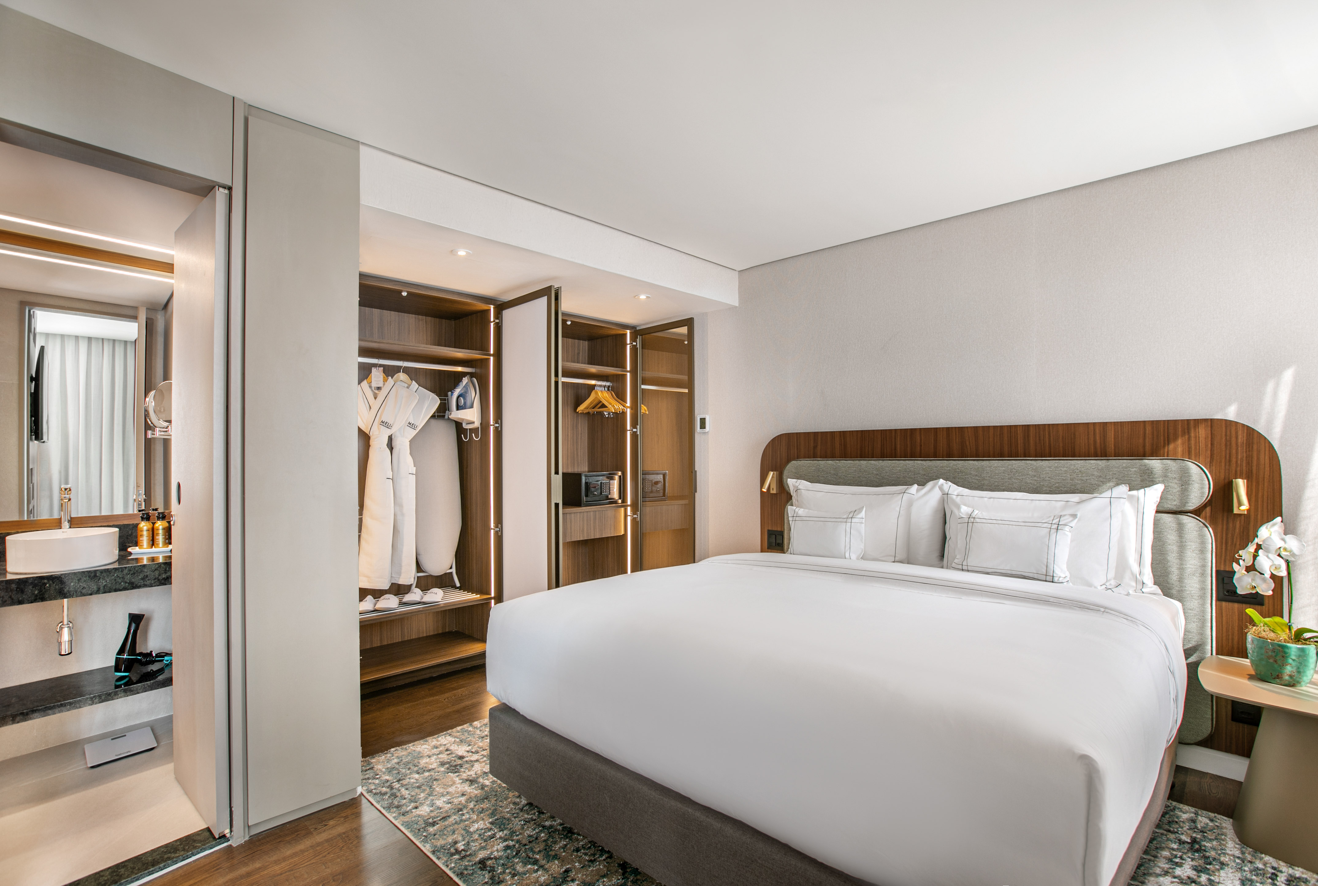 Modern hotel room with king bed, open closet, and adjoining bathroom.