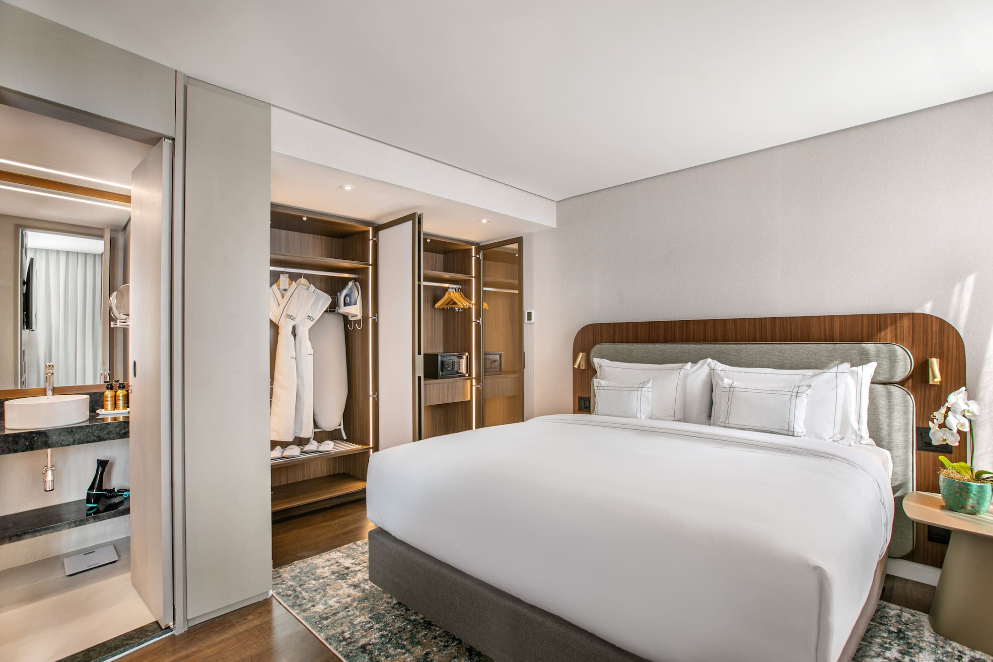 Modern hotel room with king bed, open closet, and adjoining bathroom.