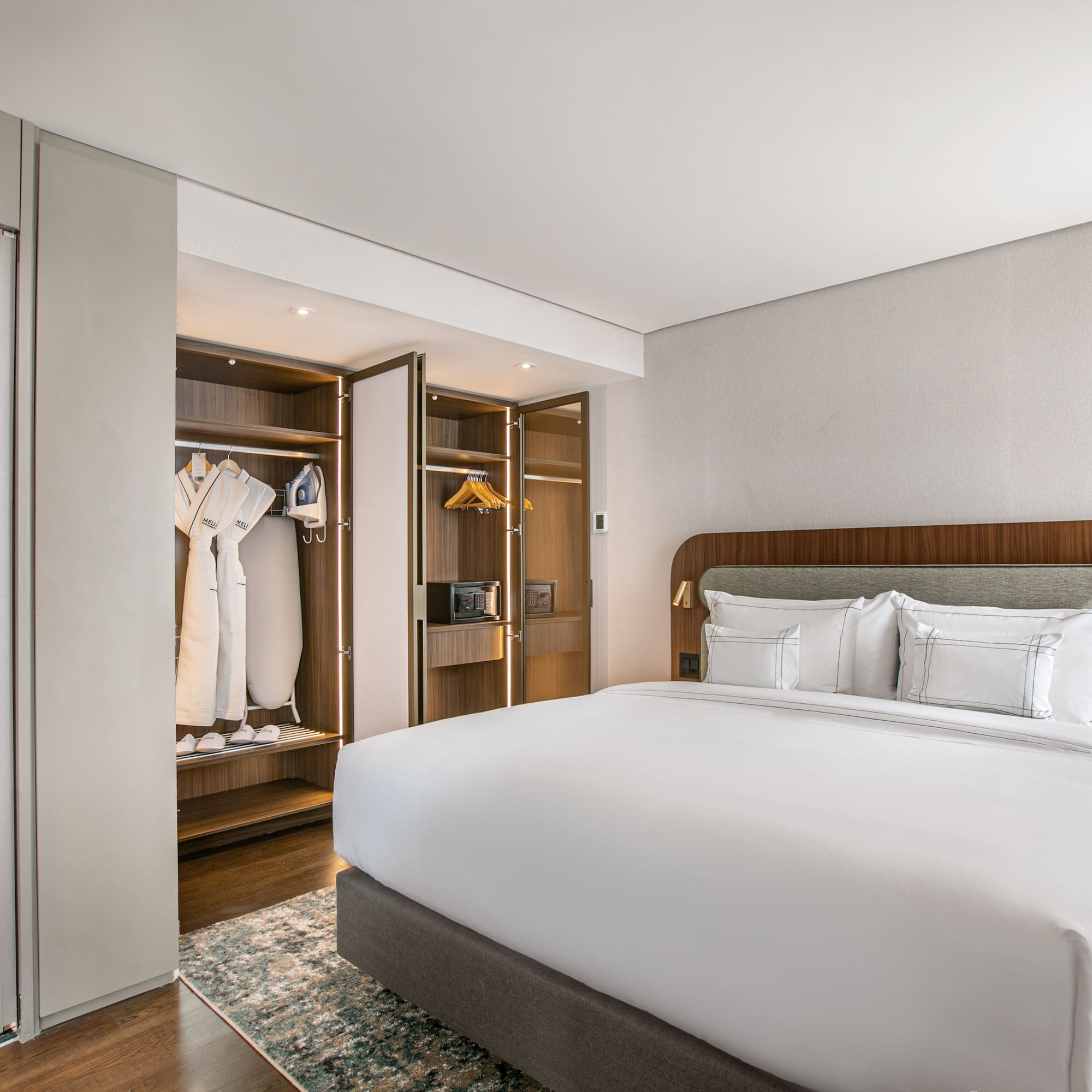 Modern hotel room with king bed, open closet, and adjoining bathroom.