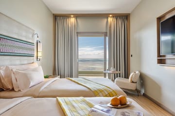 a room with two beds and a table with chairs and a window