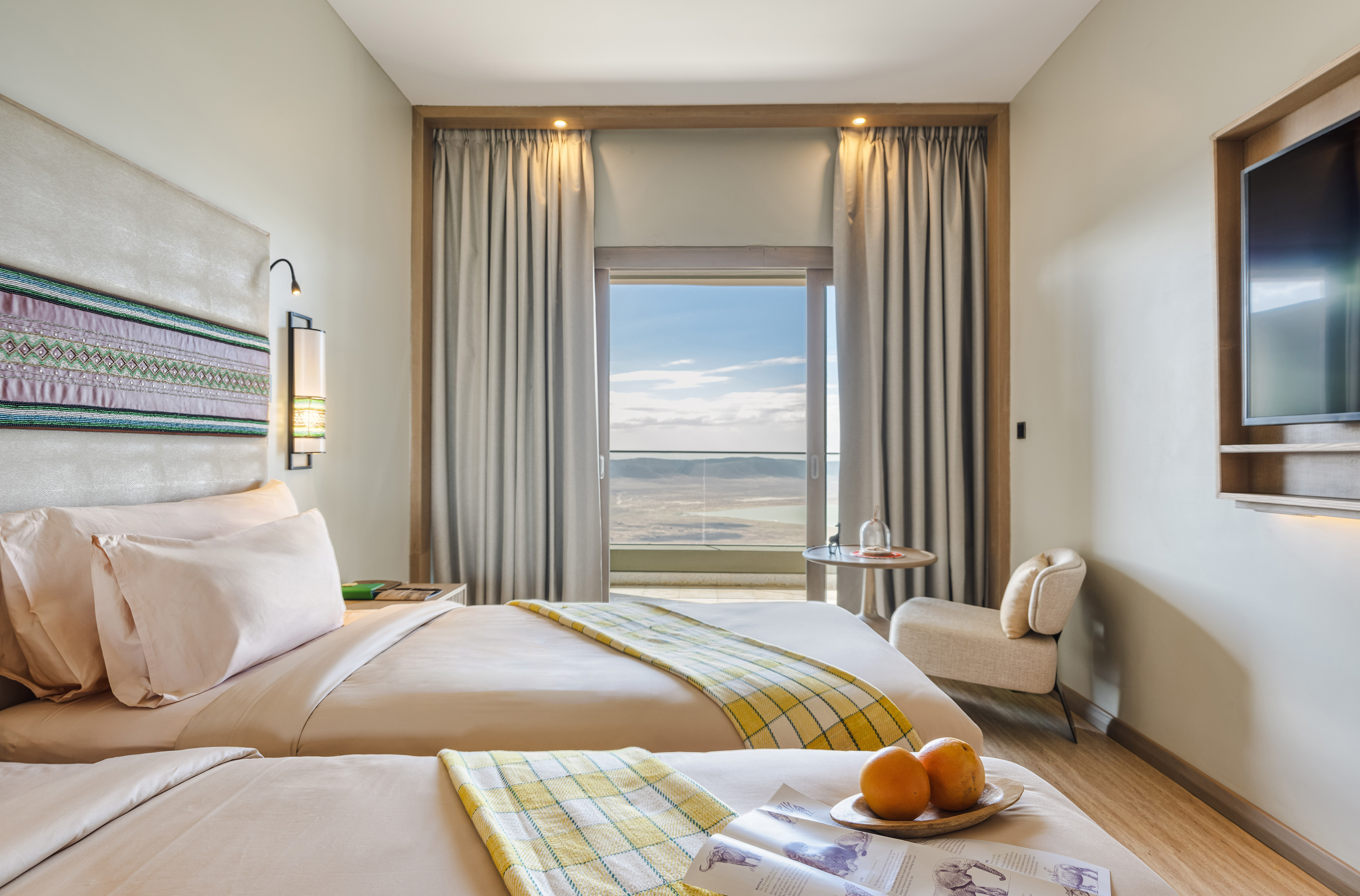 Twin bedroom in a hotel with a scenic mountain and lake view from the balcony.