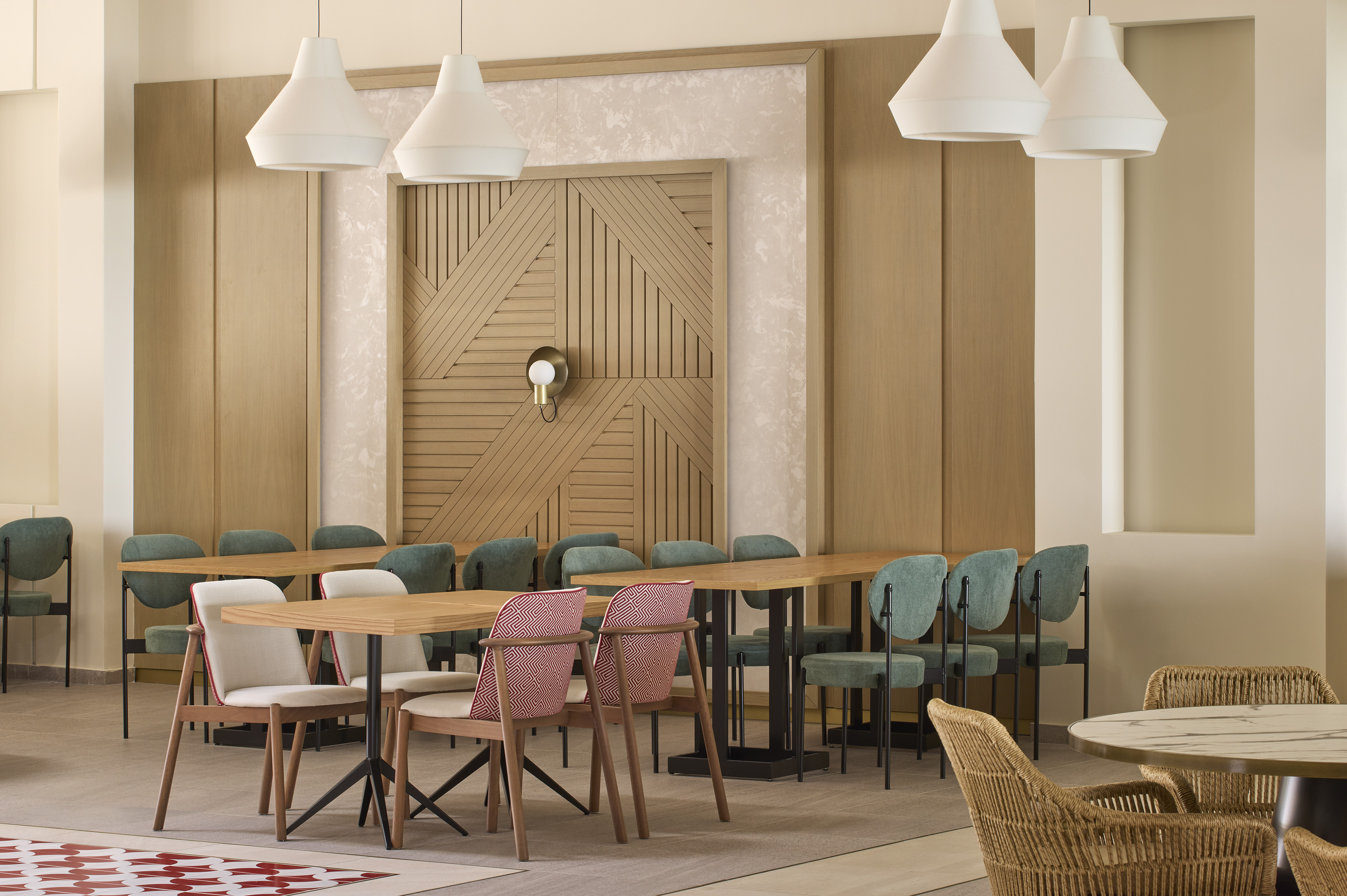 Modern restaurant interior with wooden tables, colorful chairs, and pendant lights.