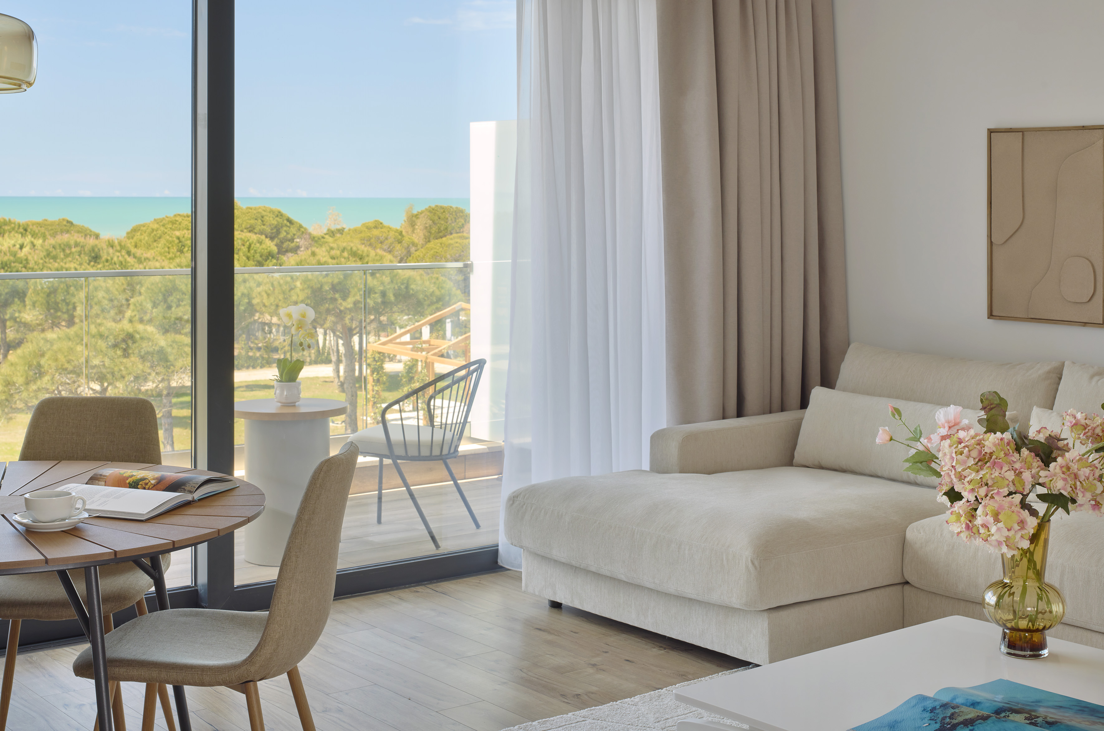 Modern living room with ocean view balcony, sofa, and dining table.