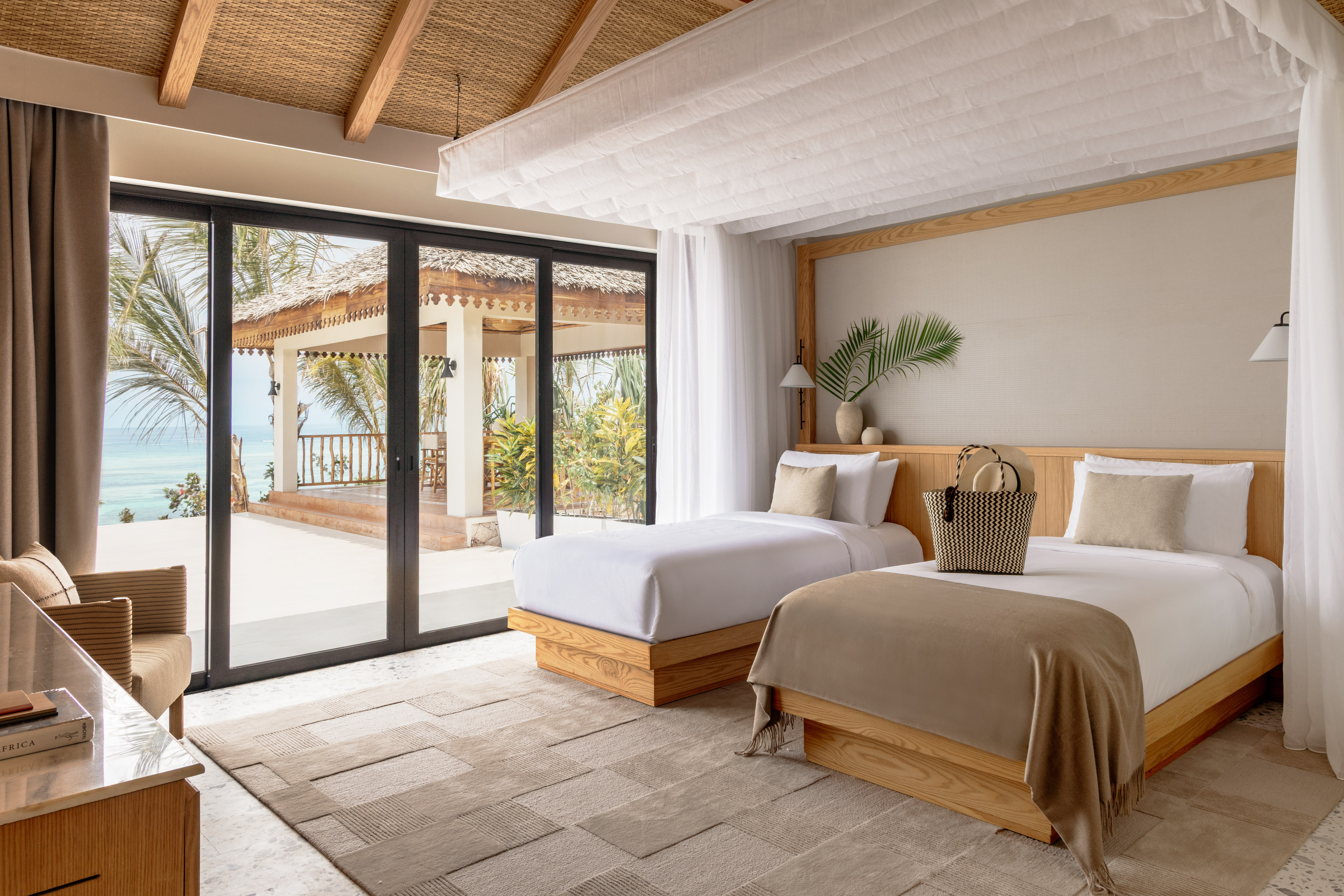 Tropical resort bedroom with twin beds, ocean view, and natural decor.