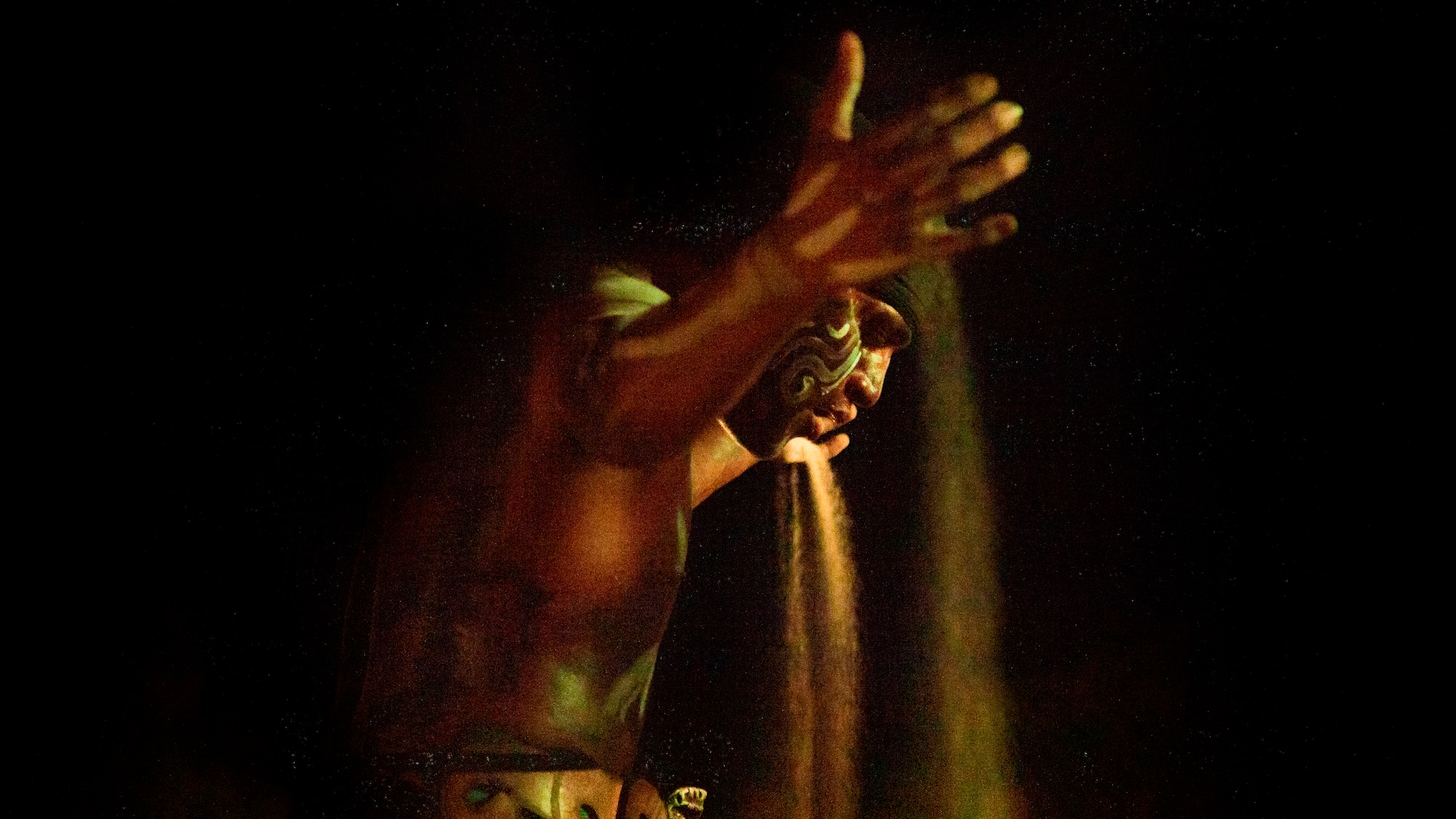 a man with a face paint pouring sand out of his hand