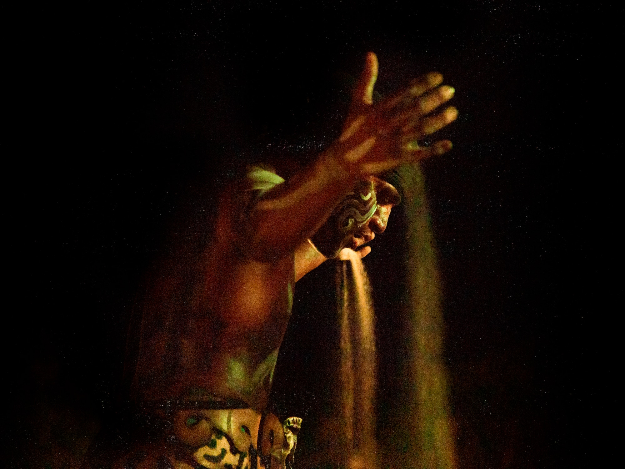 a man with a face paint pouring sand out of his hand