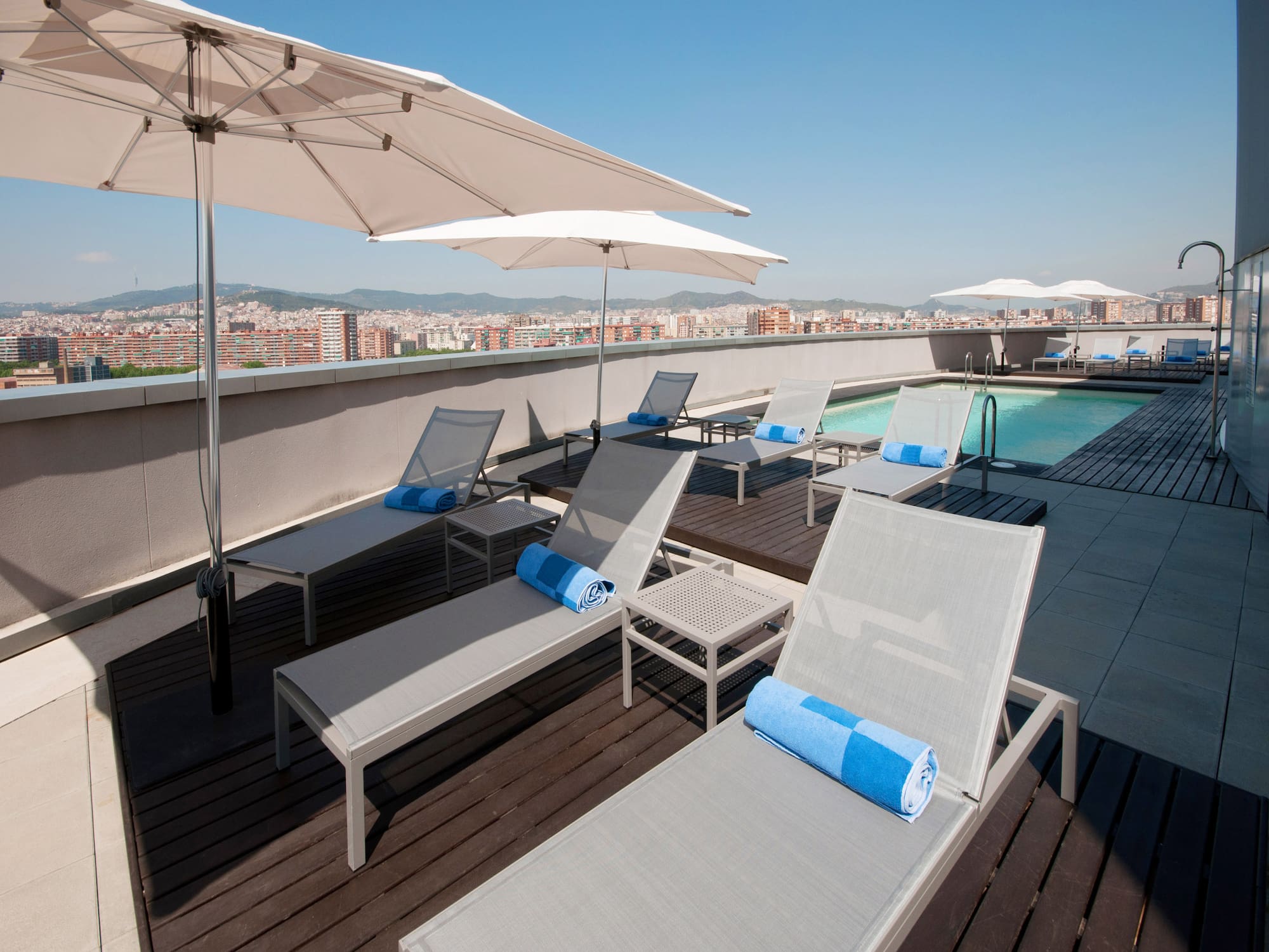 a pool with umbrellas and lounge chairs on a rooftop