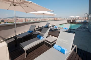 a pool with umbrellas and lounge chairs on a rooftop