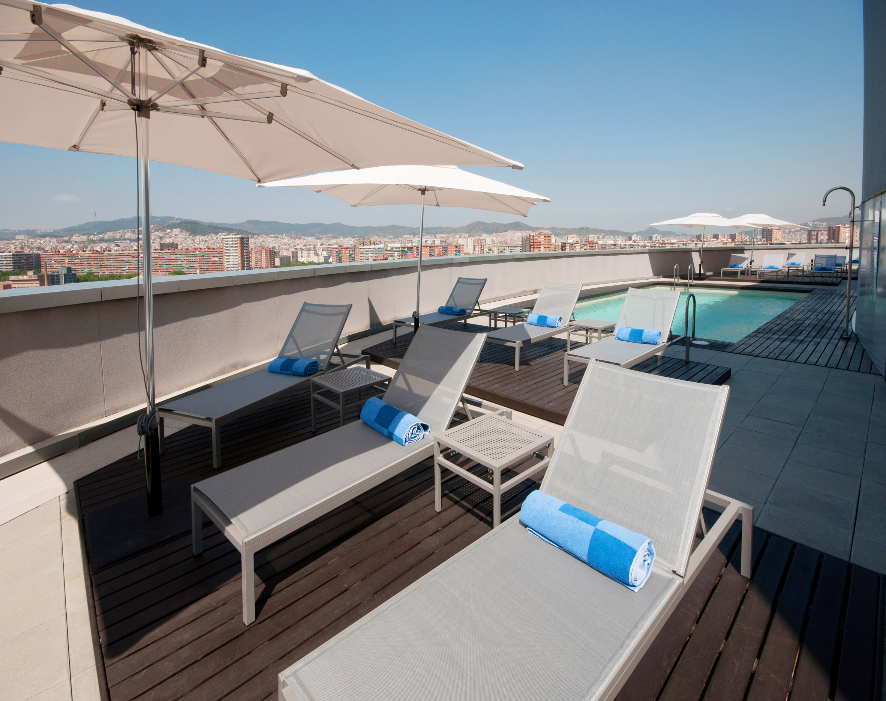 a pool with umbrellas and lounge chairs on a rooftop