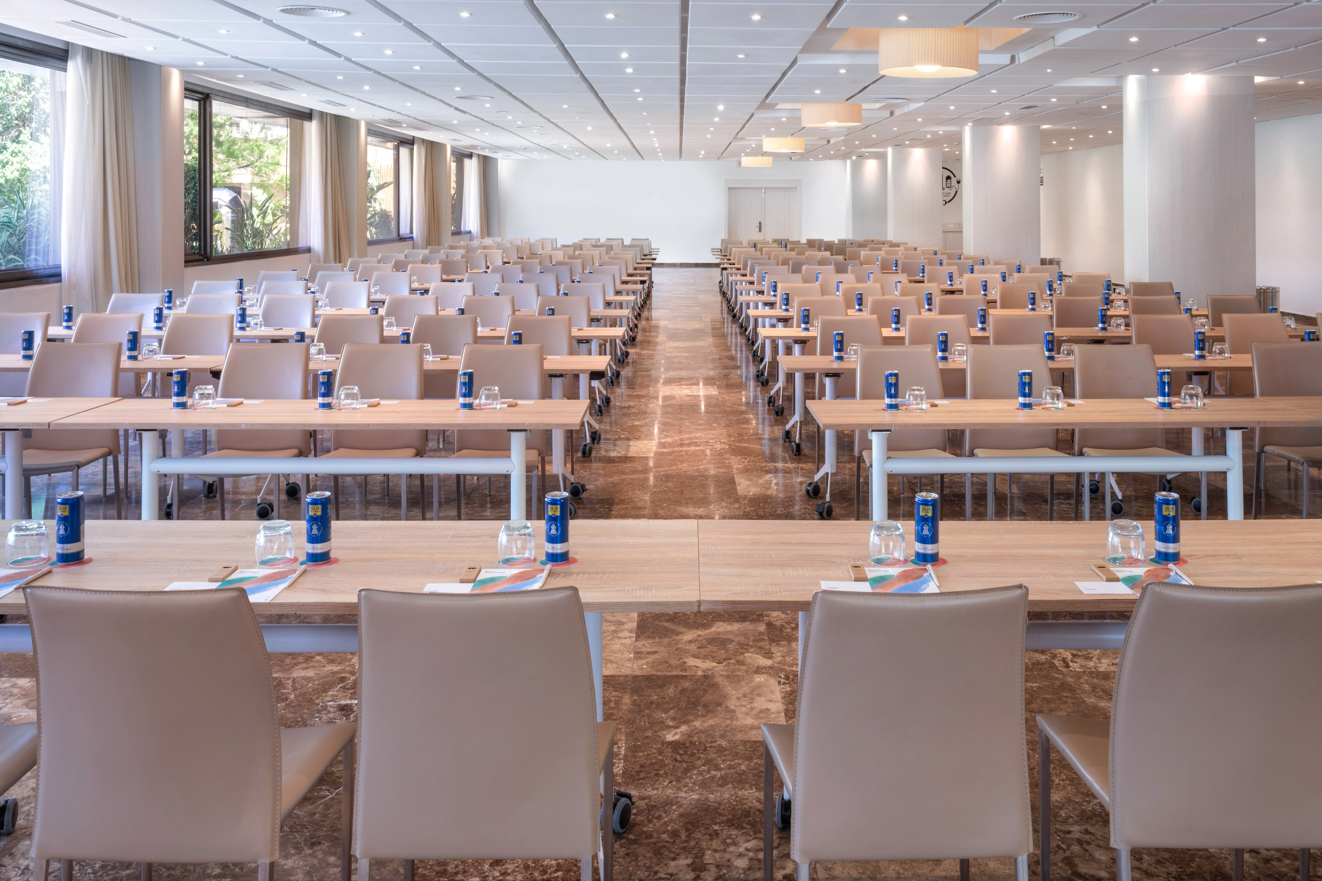 Empty modern conference room with tables, chairs, and natural light.