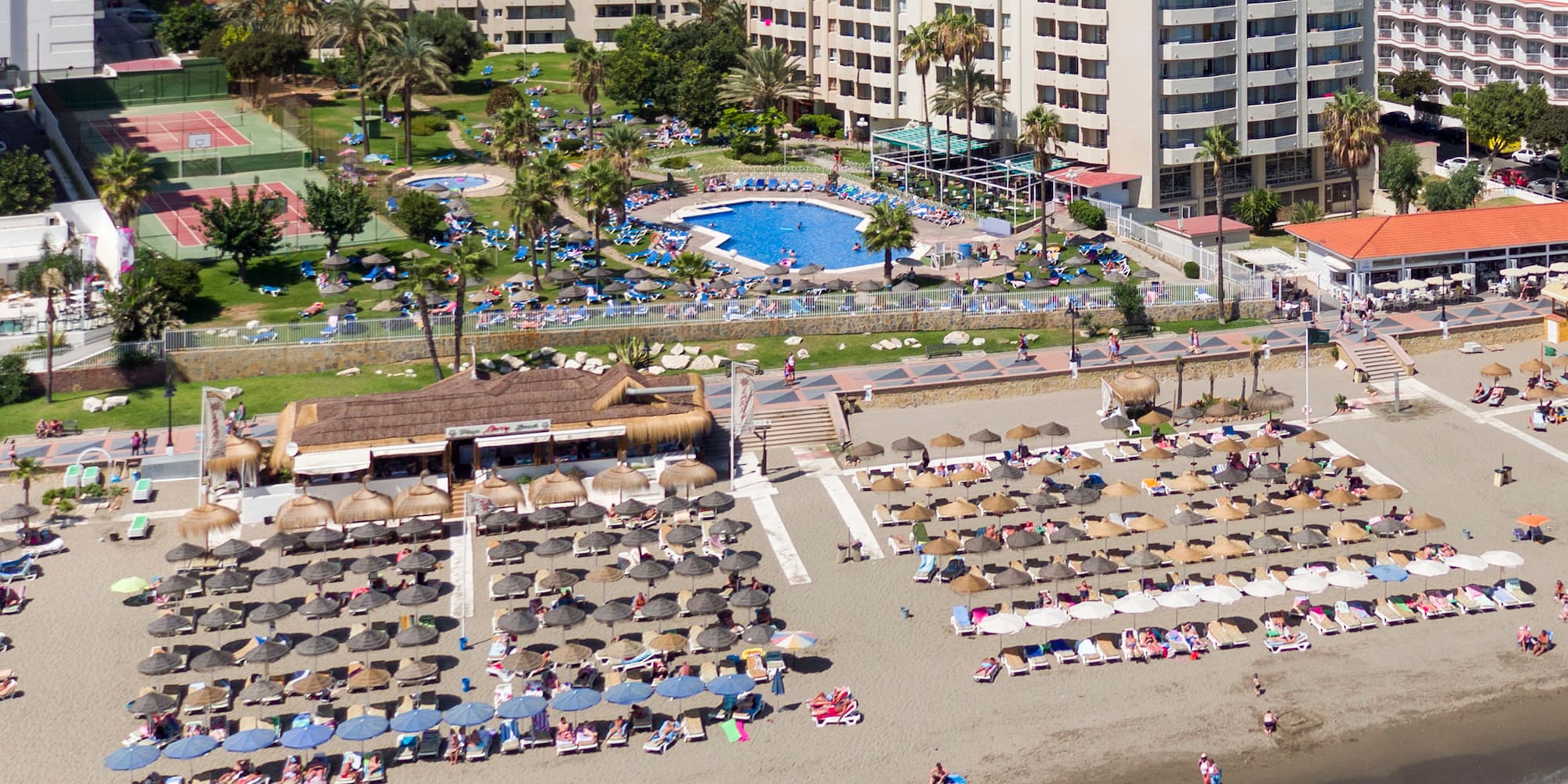 a beach with umbrellas and chairs and a swimming pool