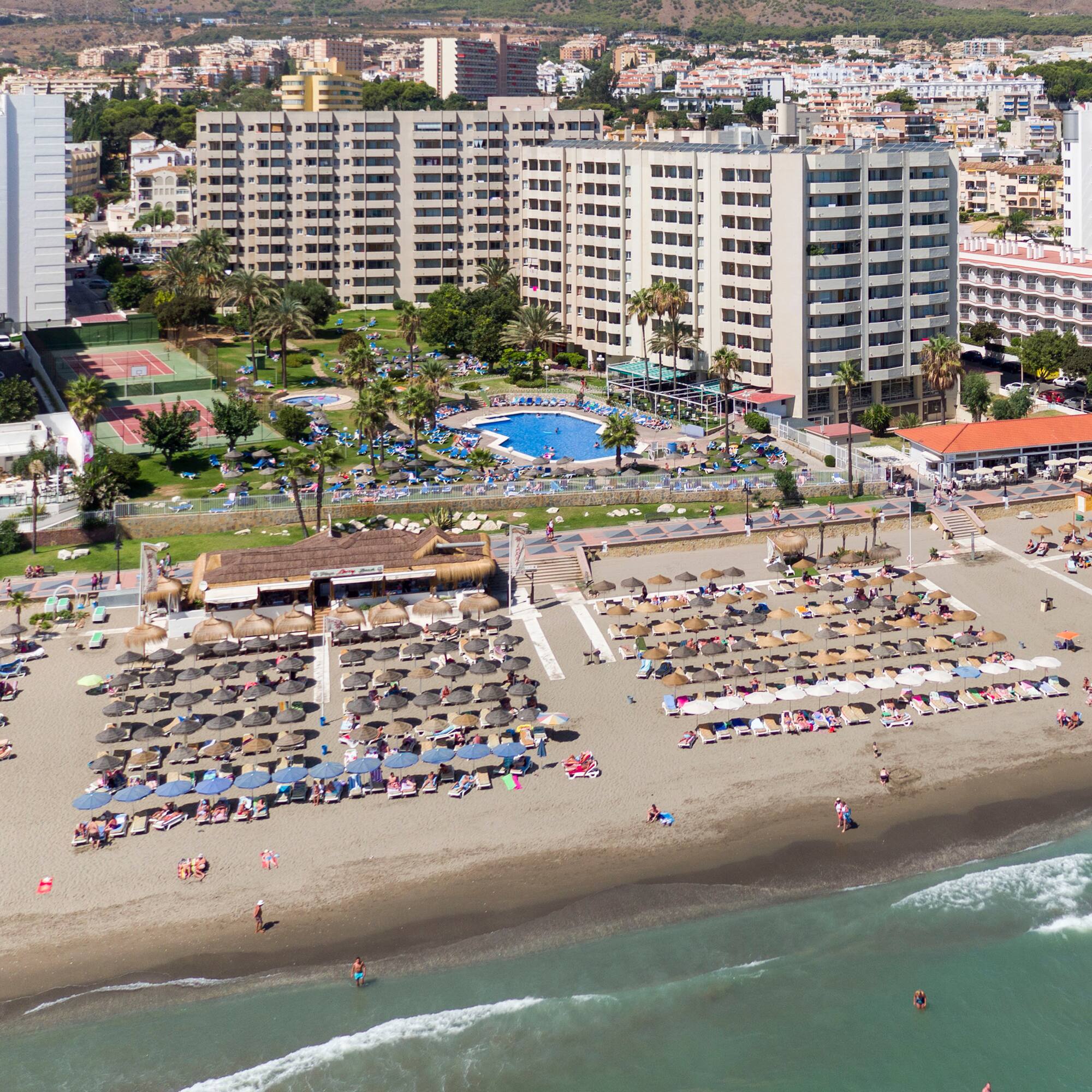 a beach with umbrellas and chairs and a swimming pool