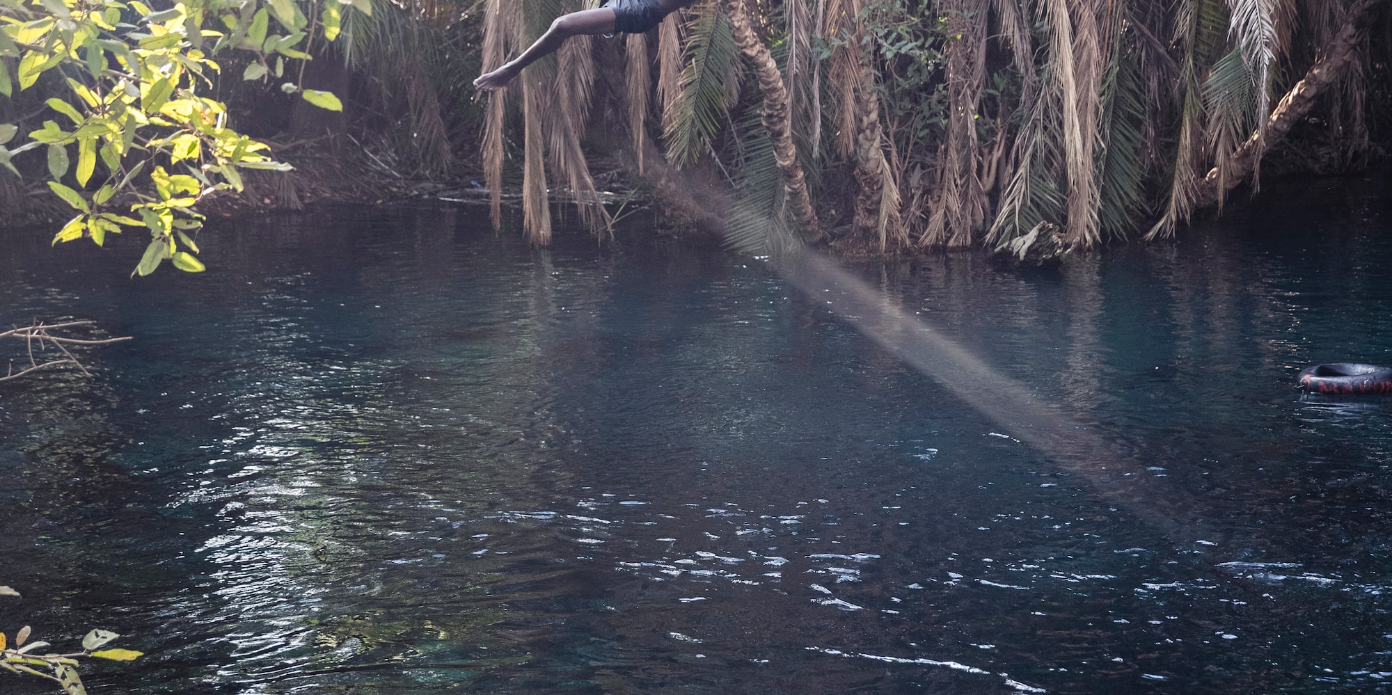 a person swinging on a rope in a river