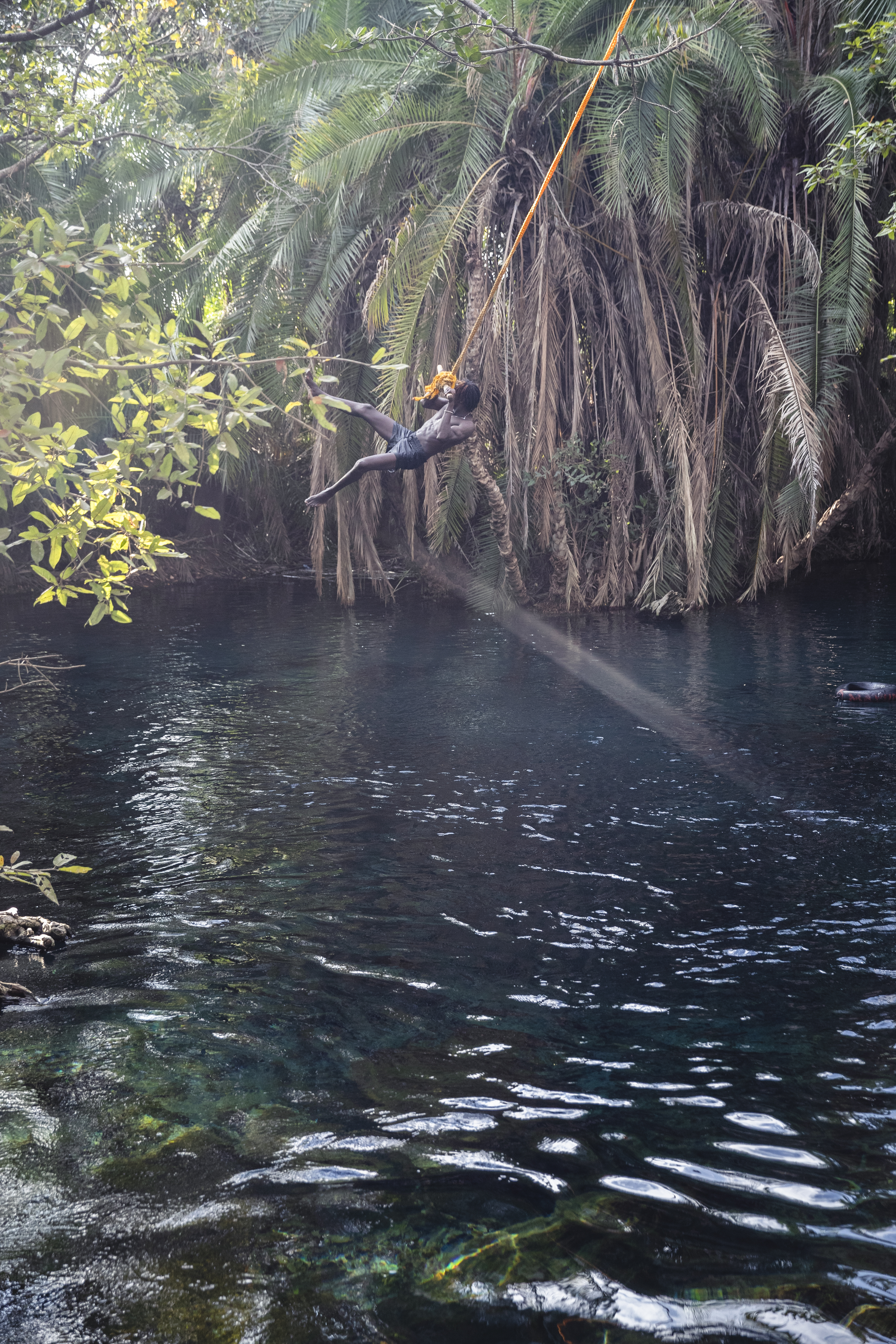 a person swinging on a rope in a river