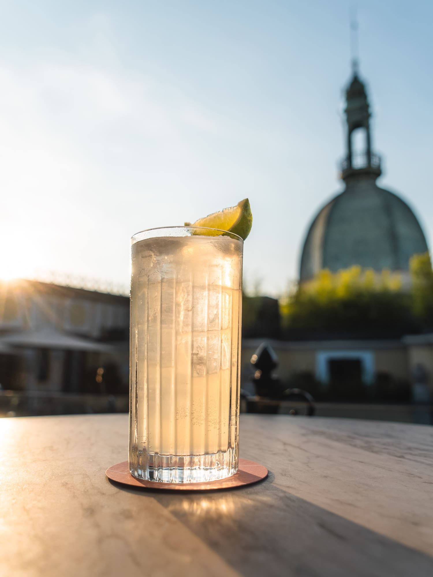 a glass of liquid with a lime wedge on a table