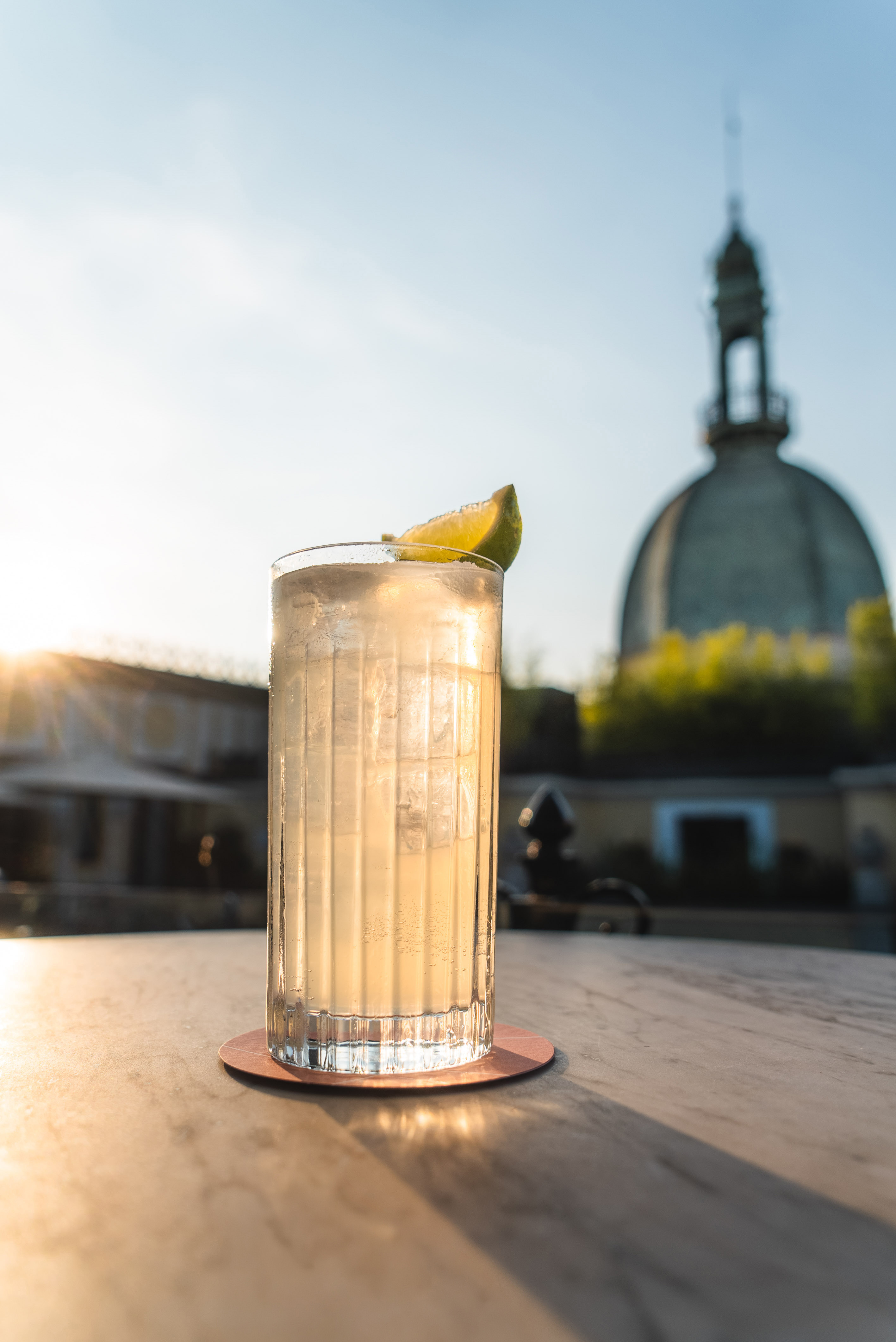 a glass of liquid with a lime wedge on a table