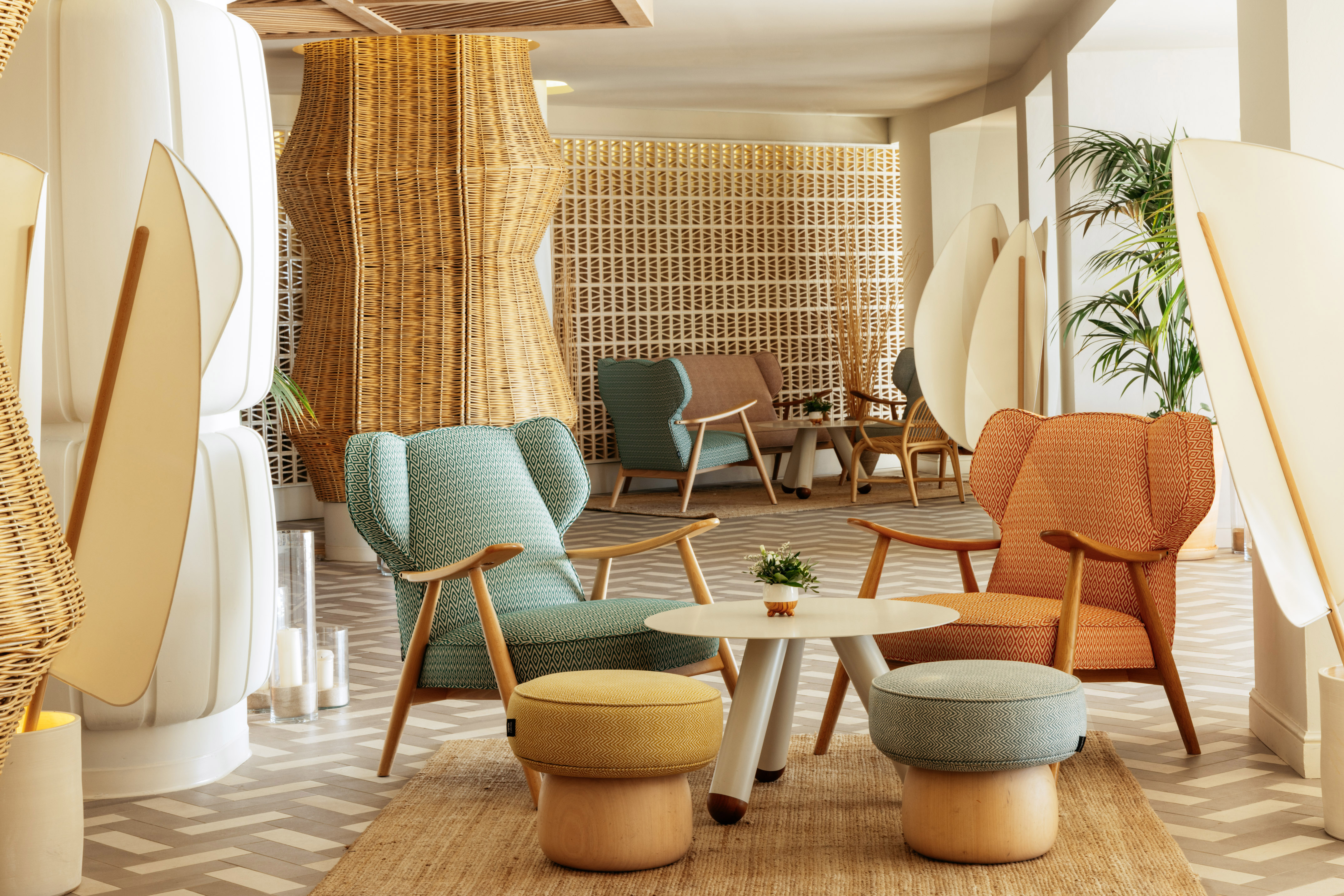 Modern lounge with colorful wingback chairs, rattan, and patterned flooring.