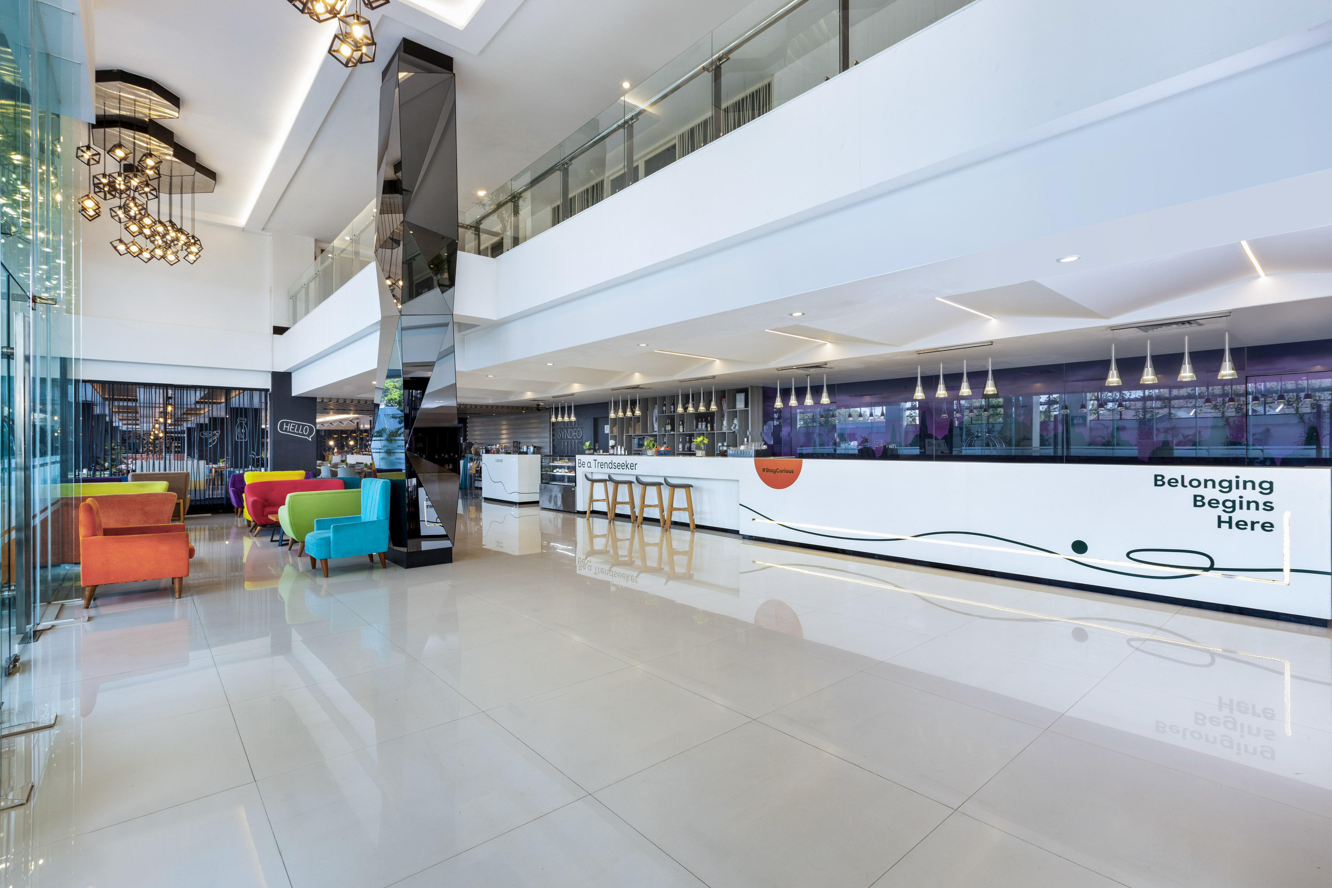 Modern hotel lobby with colorful lounge chairs, bright reception, and chic lighting.