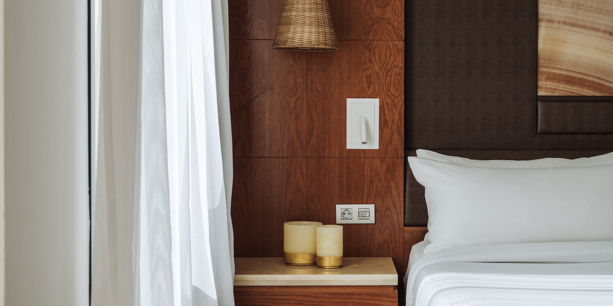 a bed with white sheets and a lamp on a table