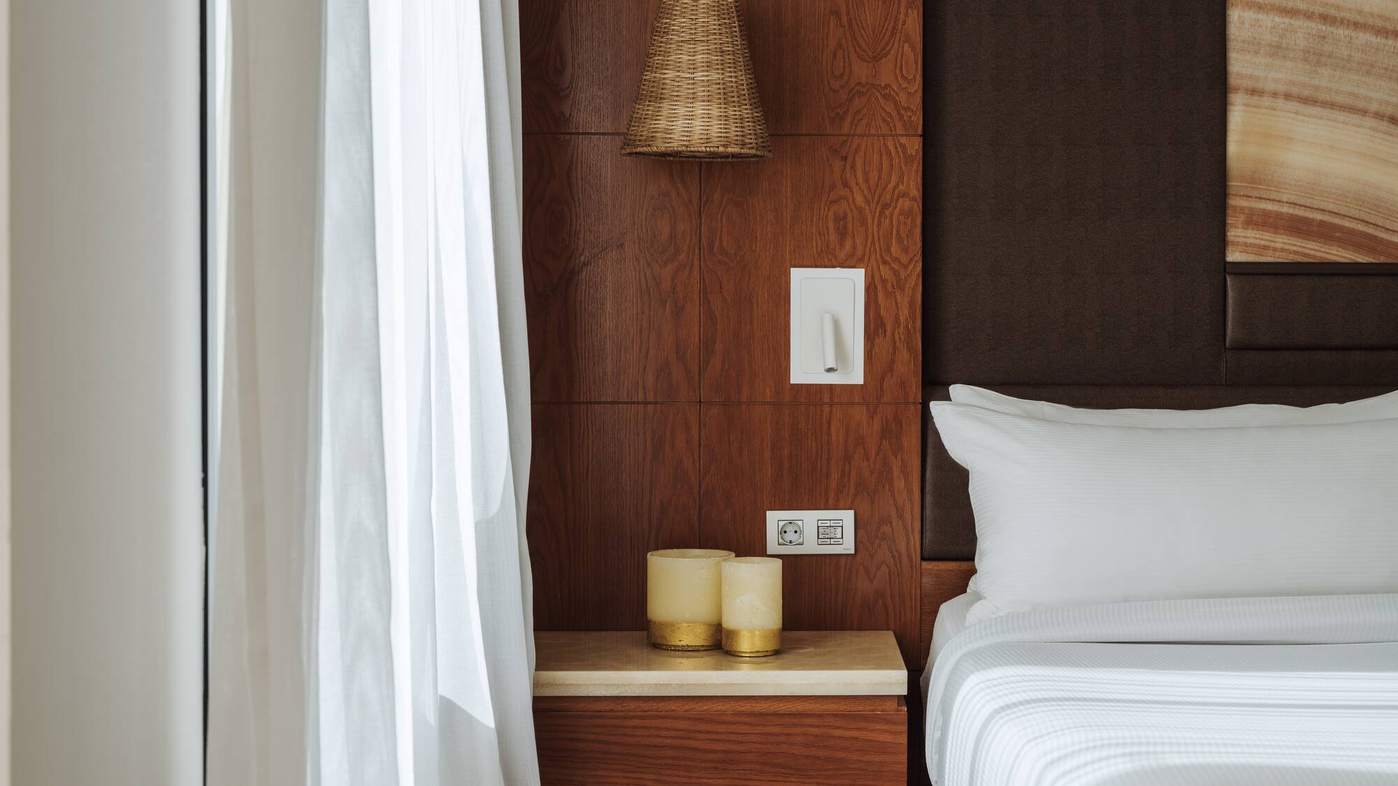 a bed with white sheets and a lamp on a table