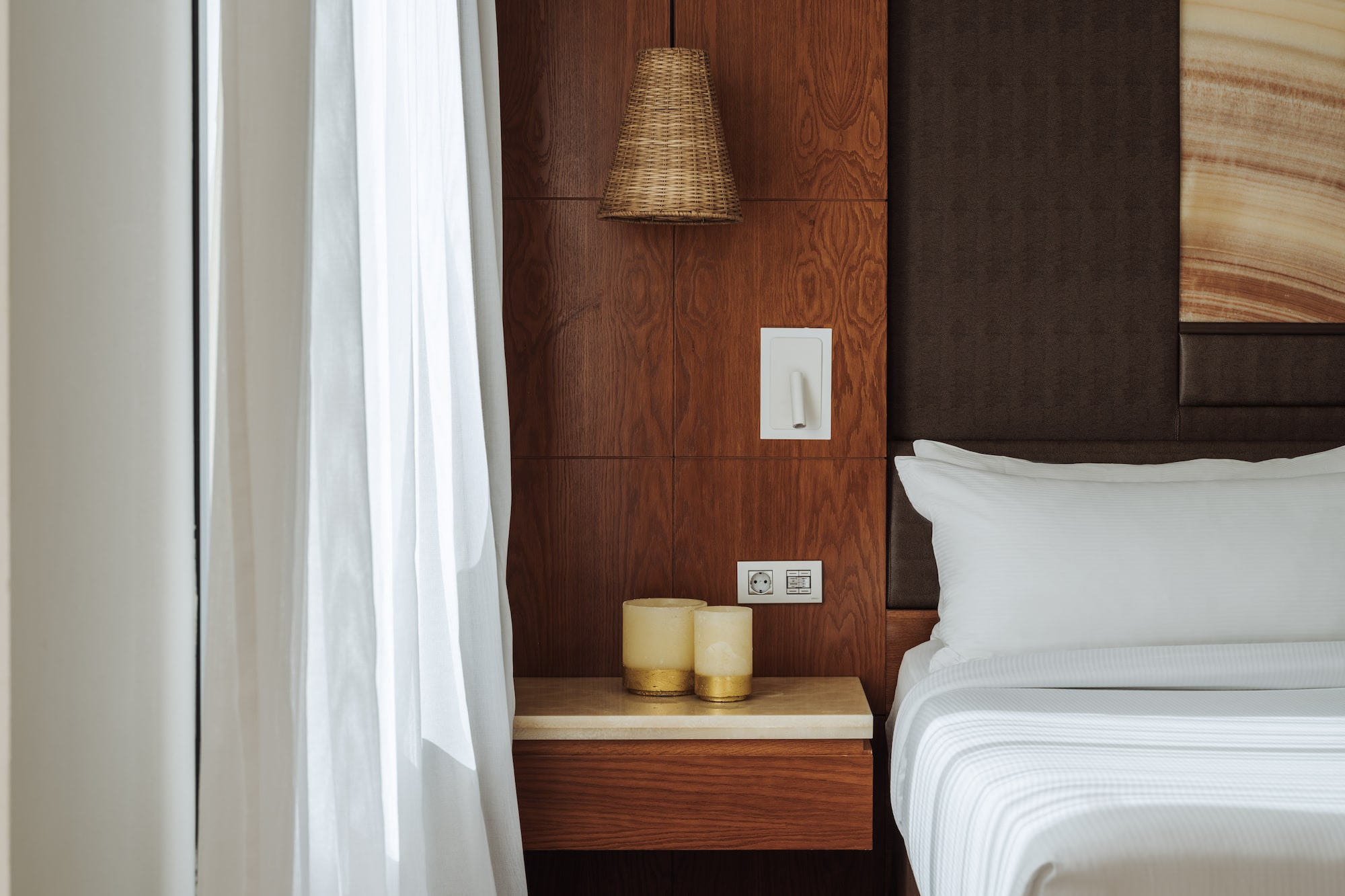 a bed with white sheets and a lamp on a table