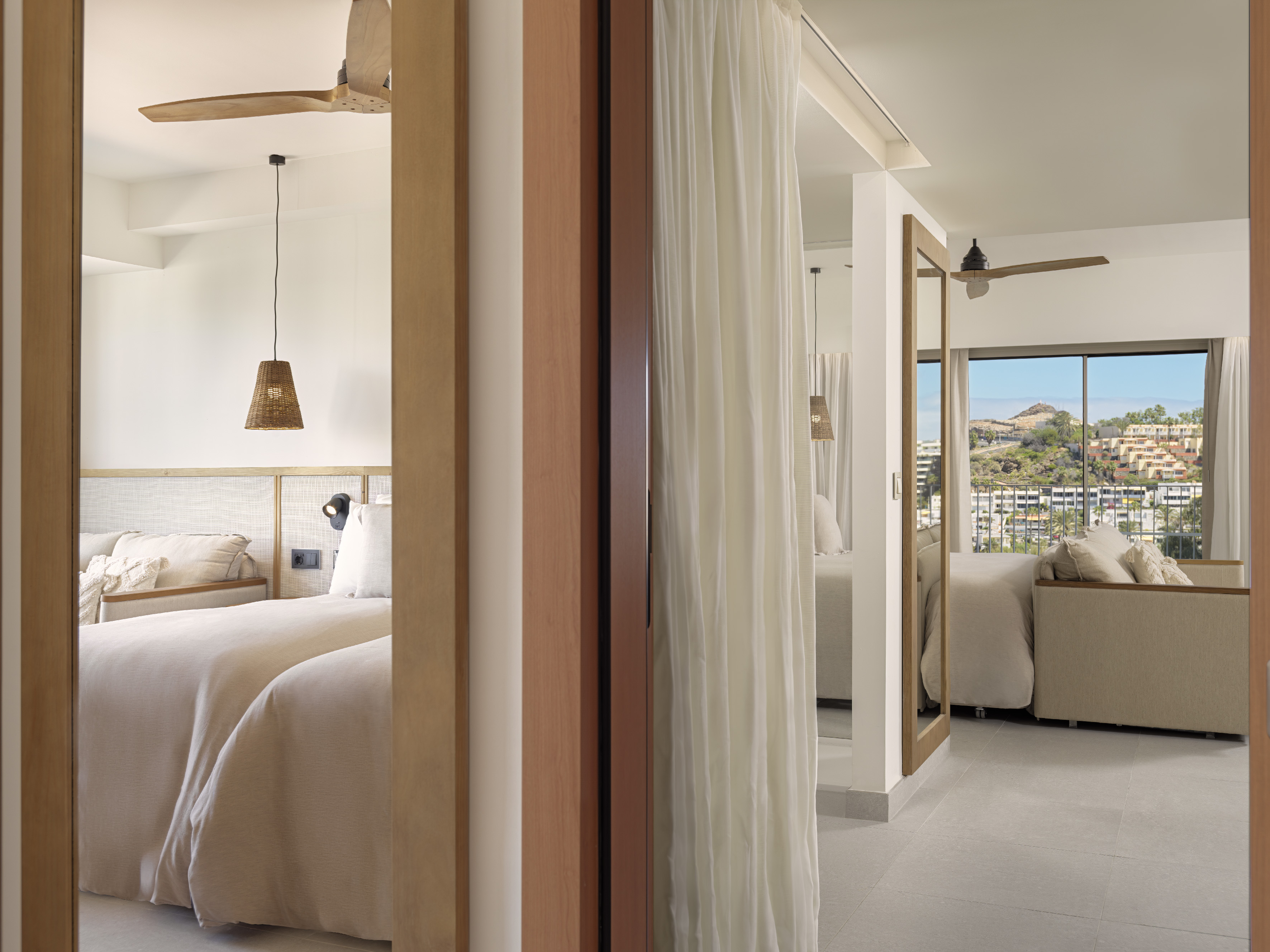 Modern hotel suite with natural decor, bedroom area, living space, and resort view.
