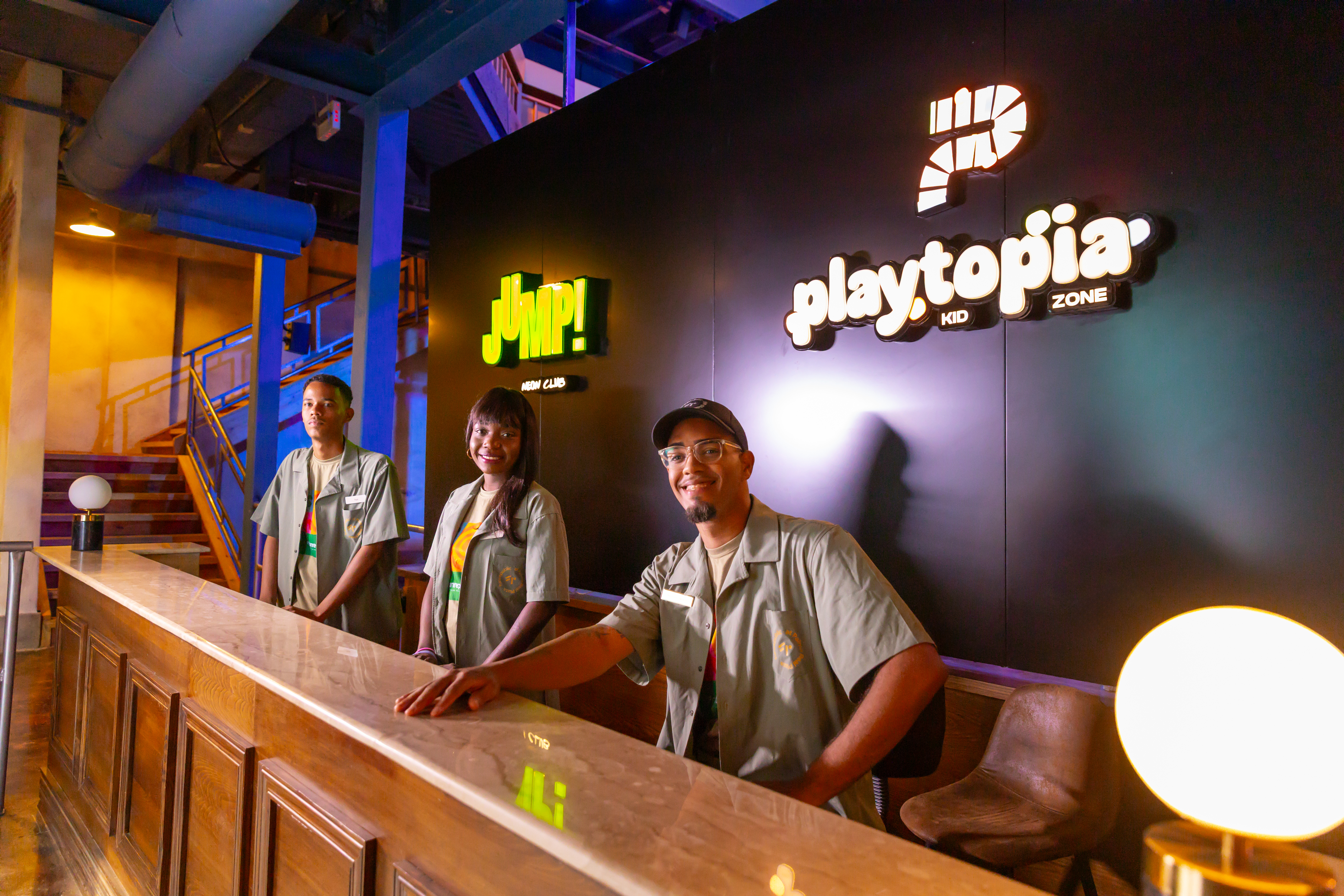 Smiling staff at JUMP! Kids Club and Playtopia Kid Zone reception.
