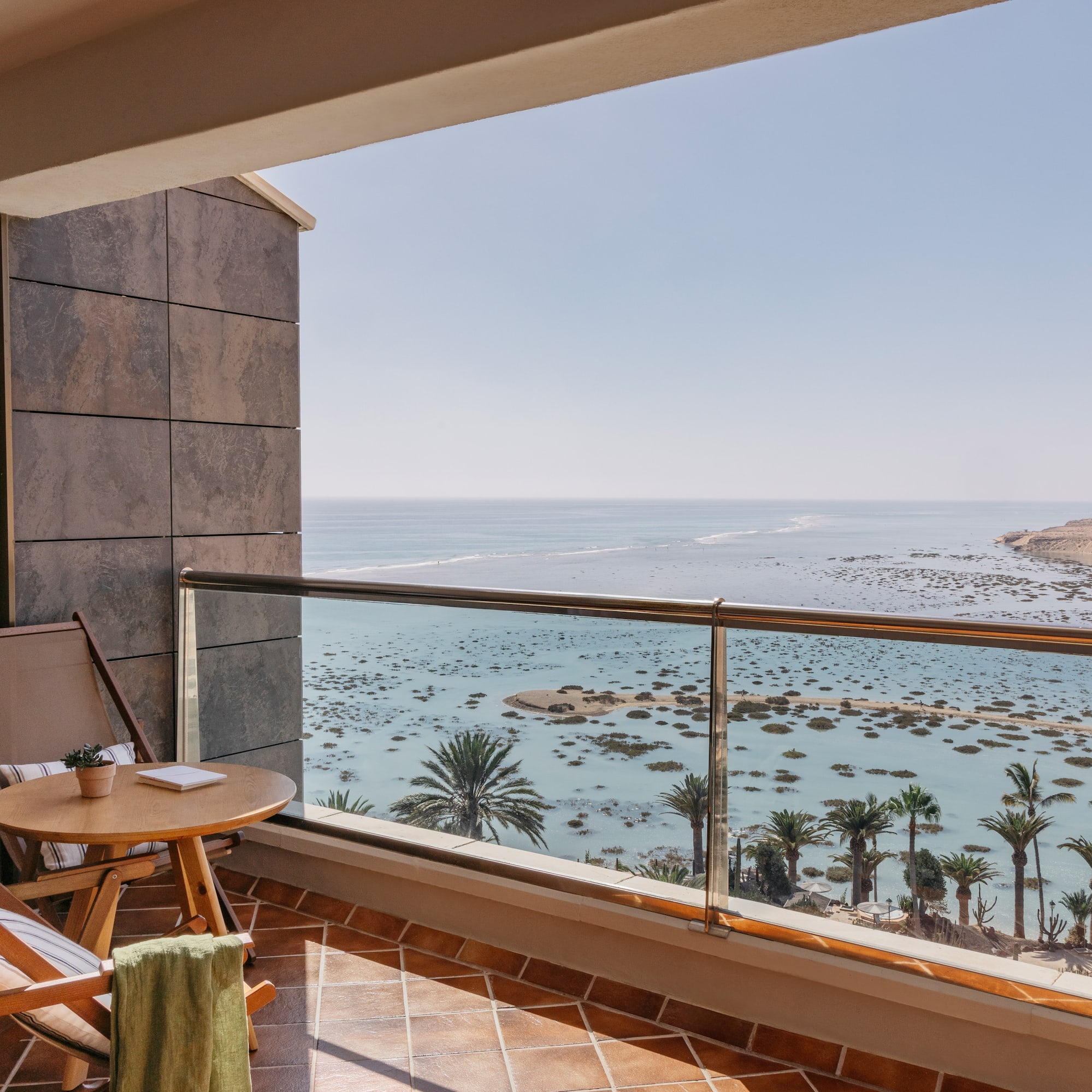 a balcony with a table and chairs overlooking the ocean