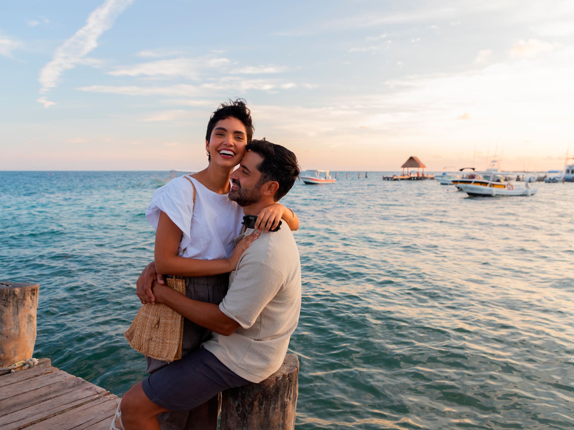 a man and woman hugging on a dock by water