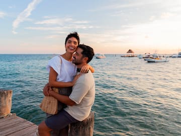 a man and woman hugging on a dock by water