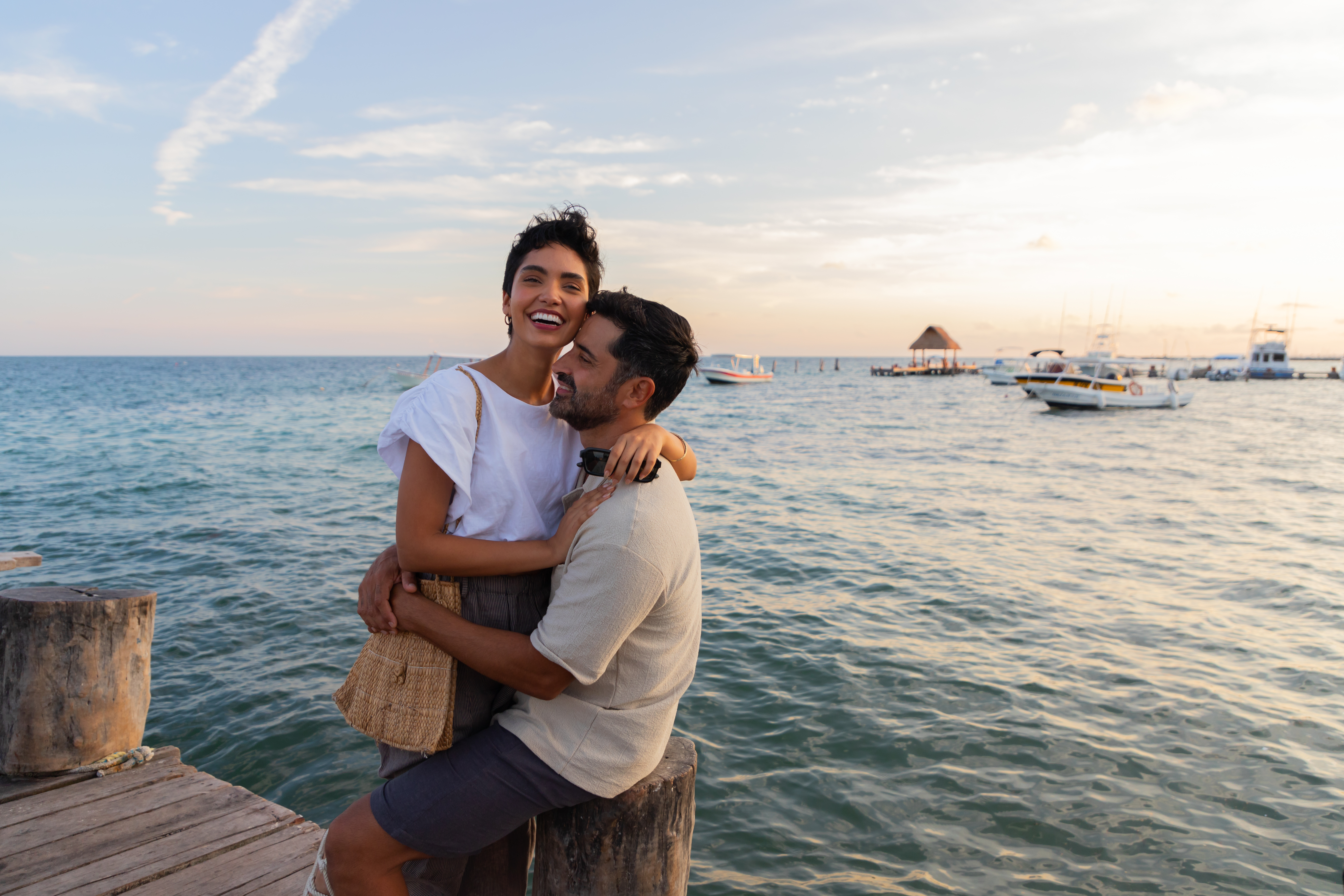 a man and woman hugging on a dock by water