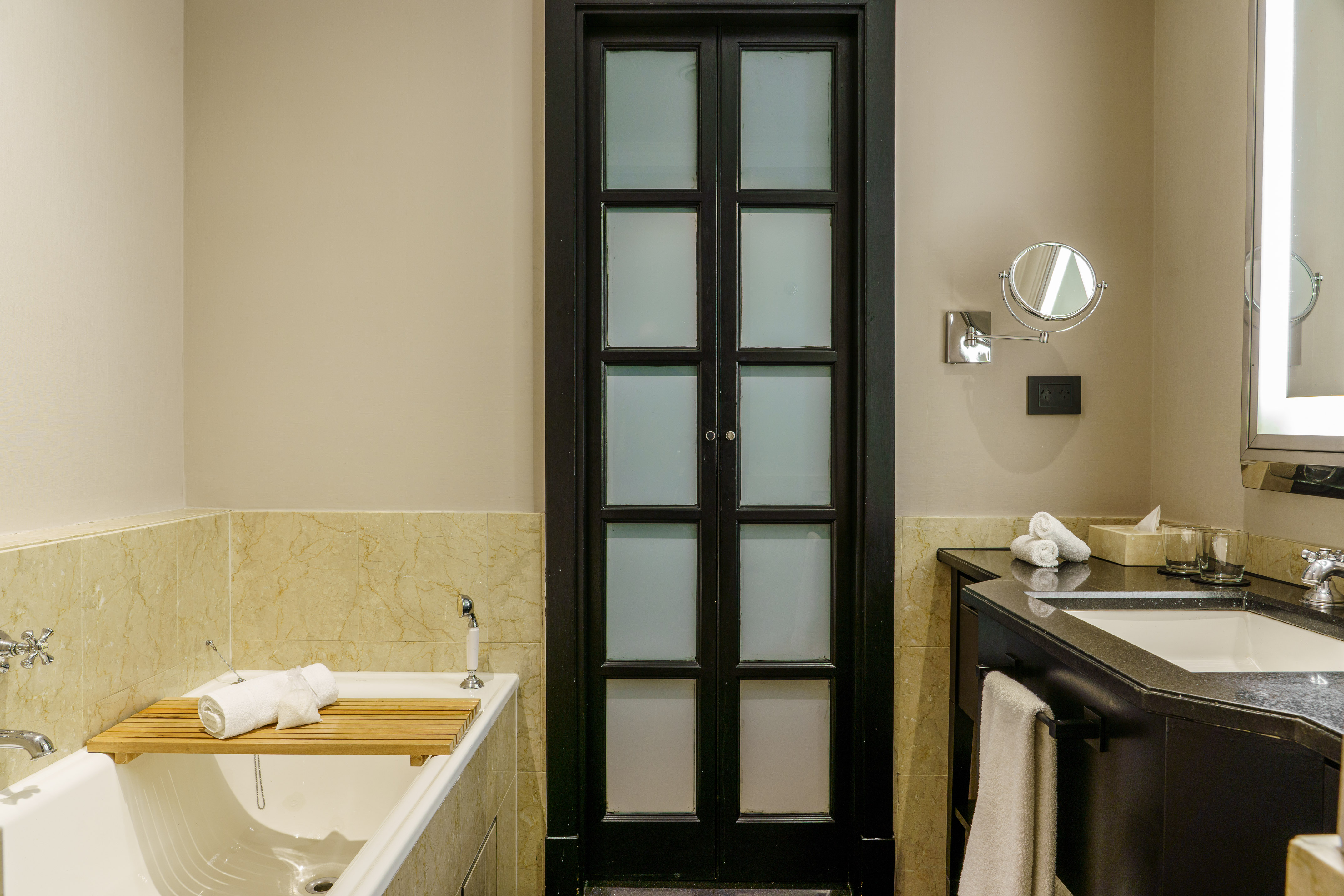 Modern bathroom with bathtub, black frosted glass doors, and vanity sink.