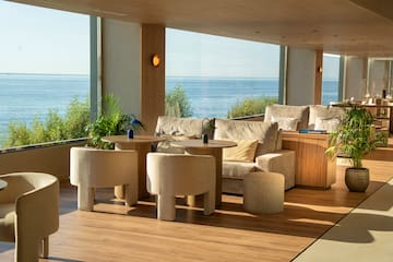 Modern coastal lounge with panoramic ocean view, contemporary seating.