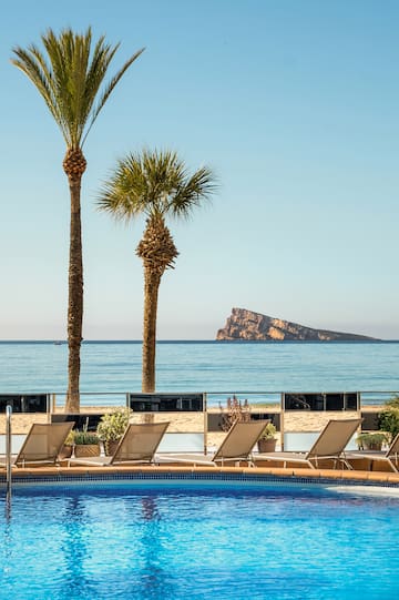 a pool with chairs and palm trees on a beach
