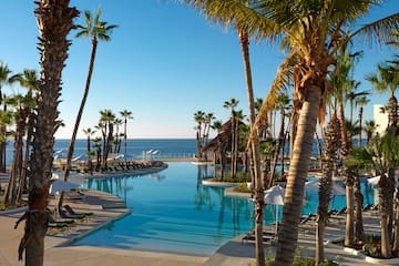 a pool with palm trees and chairs and umbrellas