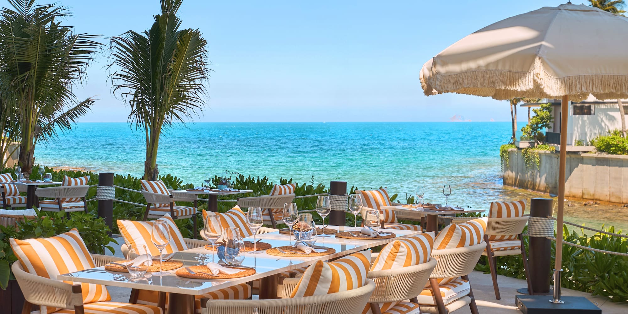 a table set up with chairs and umbrellas on a beach