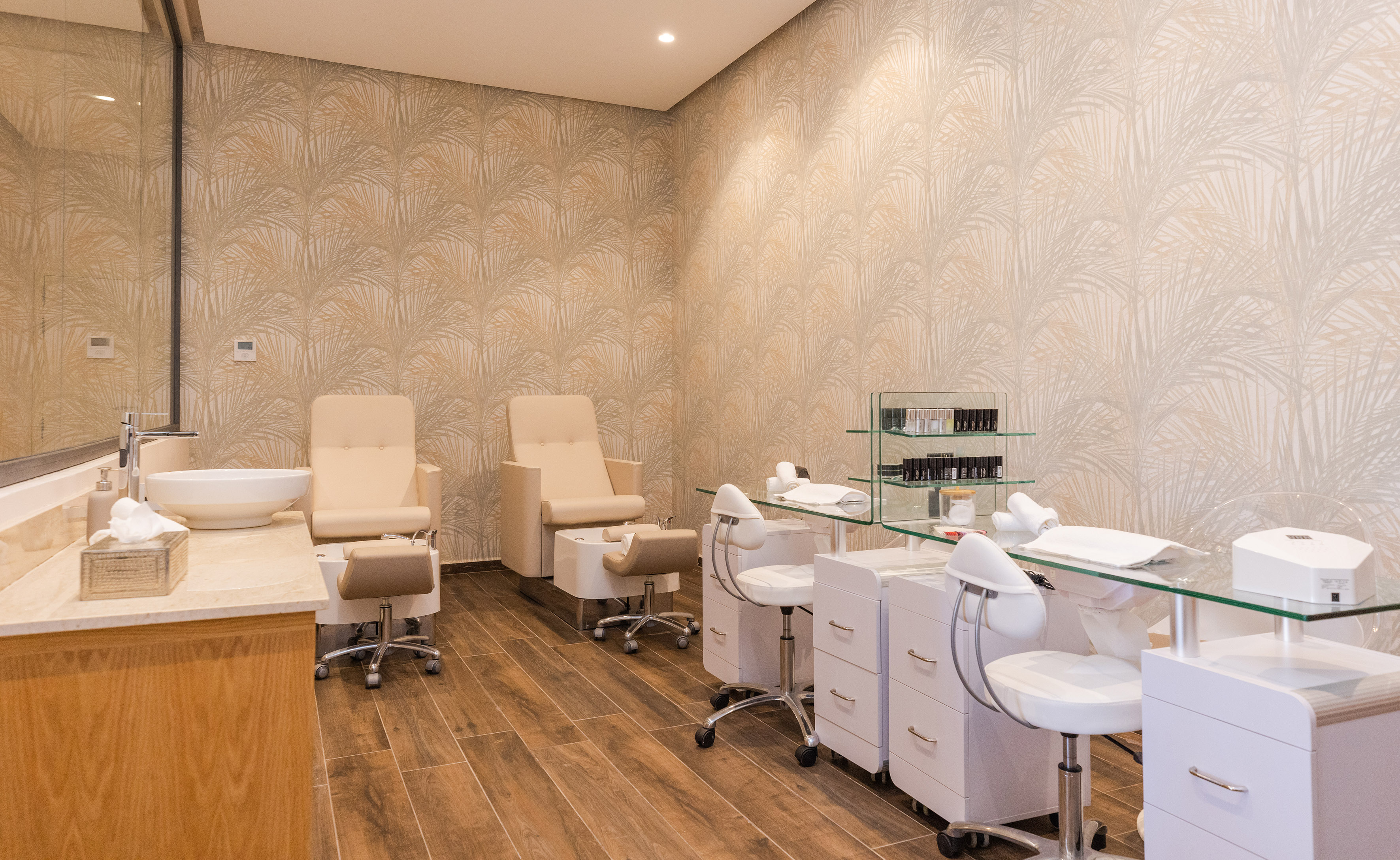Contemporary nail and pedicure spa with beige chairs and white manicure stations.