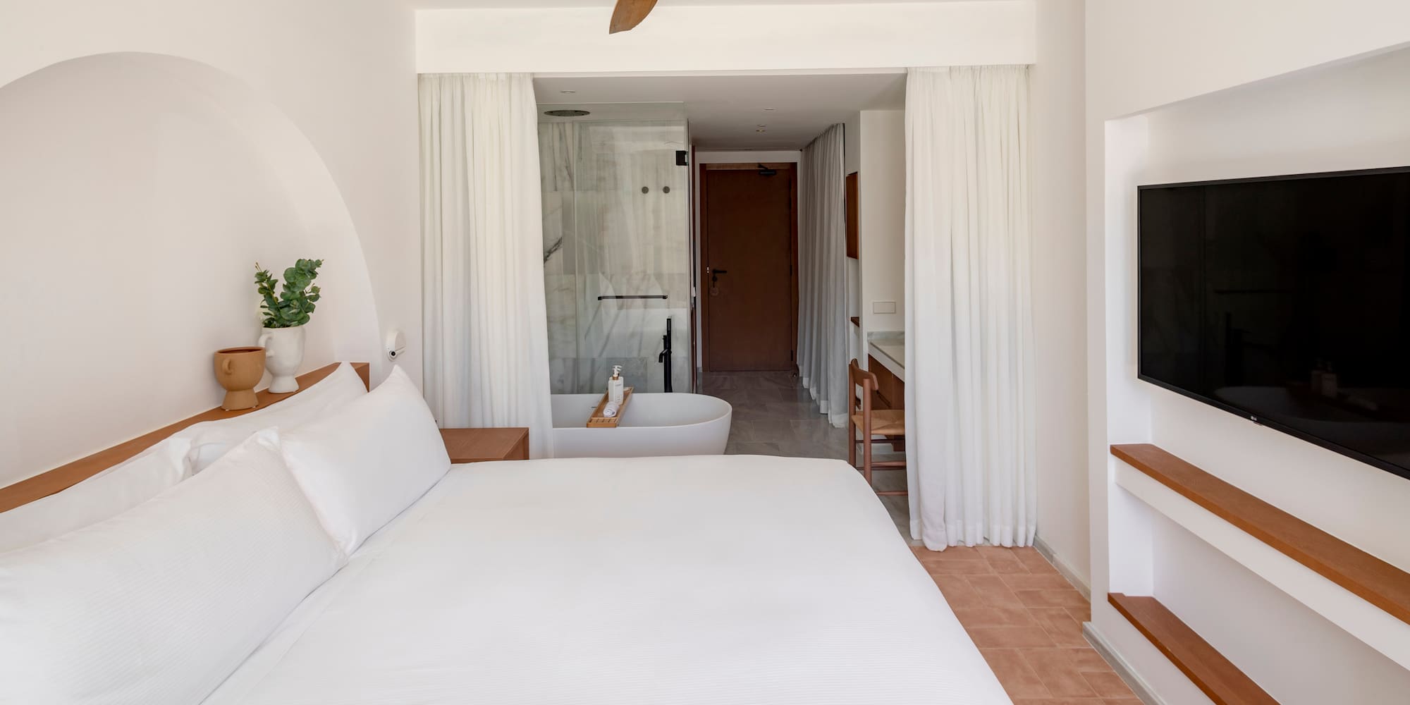 a white bed with a white ceiling fan and a bathtub